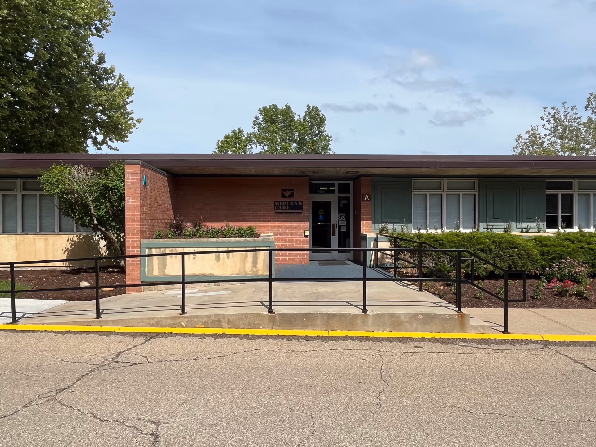 Exterior view of Midland Care Connection building with brick facade, ramp, and landscaping.