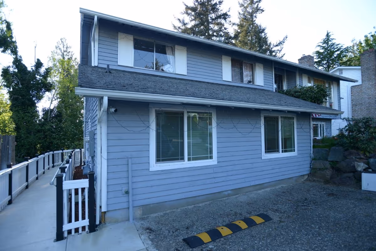 Exterior of Haniharmony Adult Family Home LLC, a two-story blue-gray building with large windows.