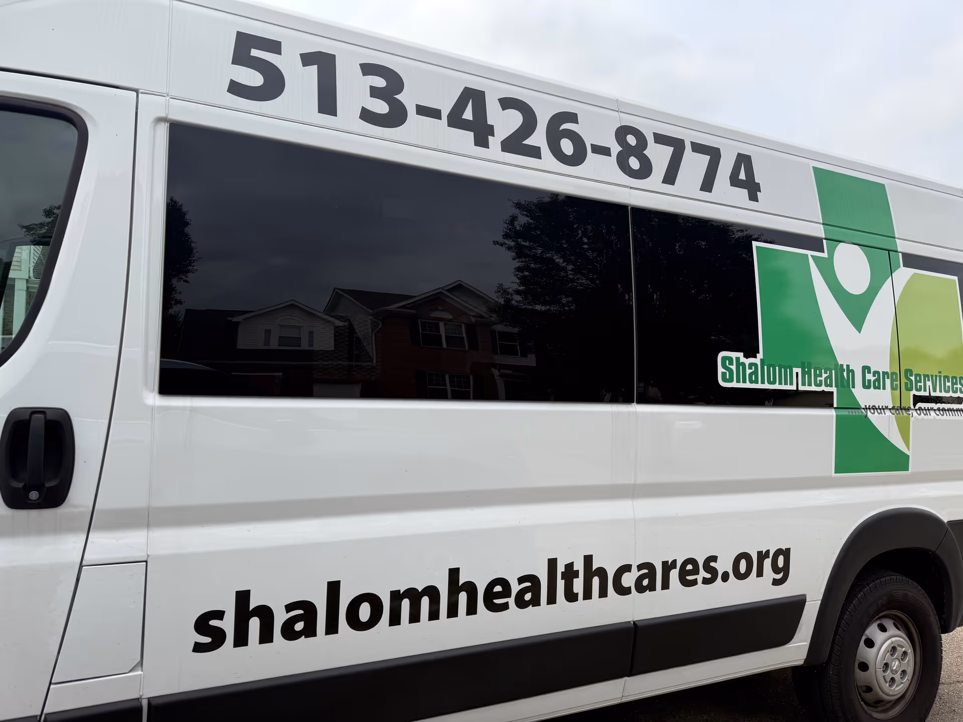 Side of a white van with Shalom Health Care logo and phone number.