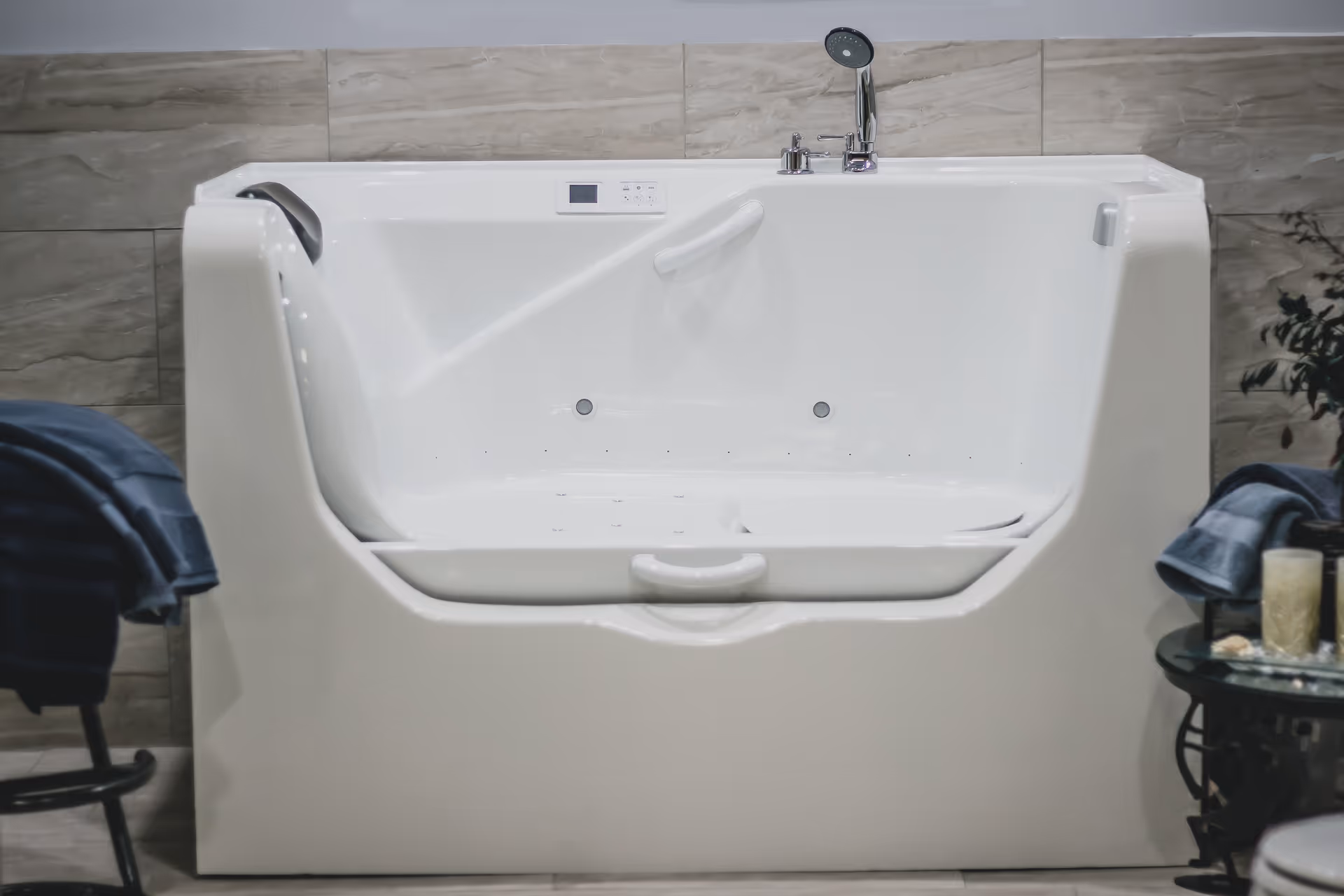 White accessible bathtub with built-in seat and chrome fixtures in a tiled bathroom.