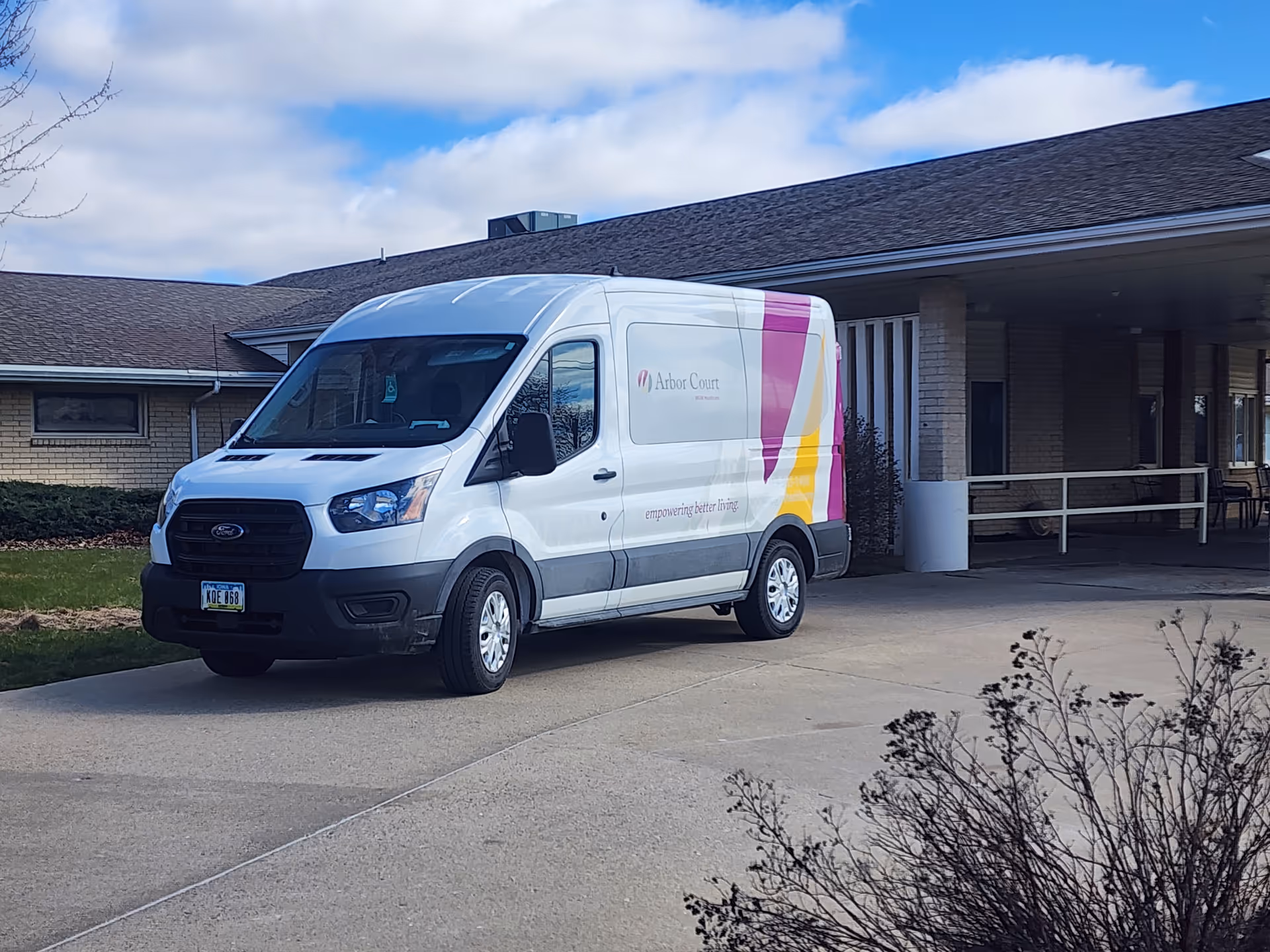 White Arbor Court van parked in front of a single-story senior living facility entrance.