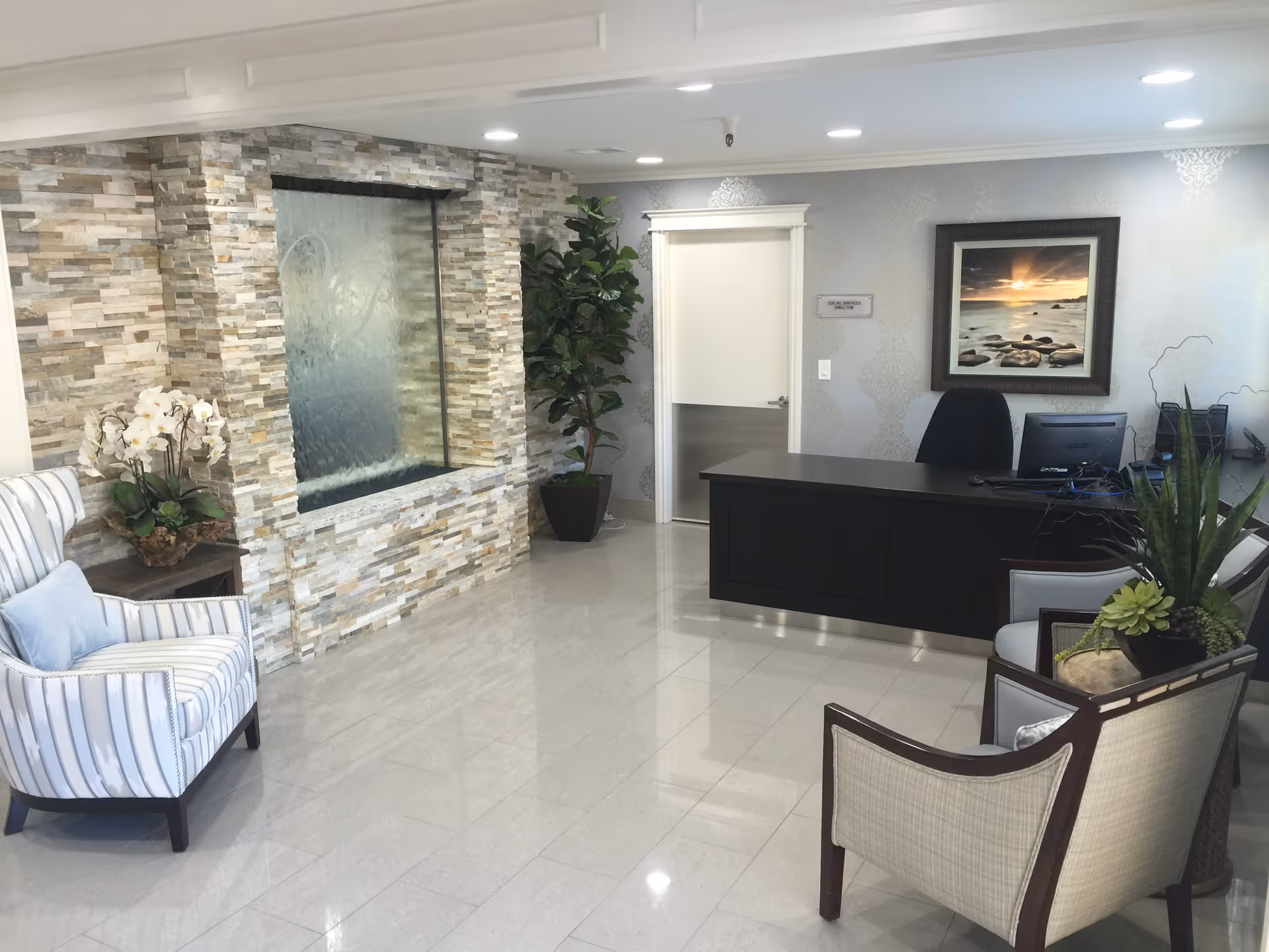 A modern reception lobby with a stone water feature and seating area.