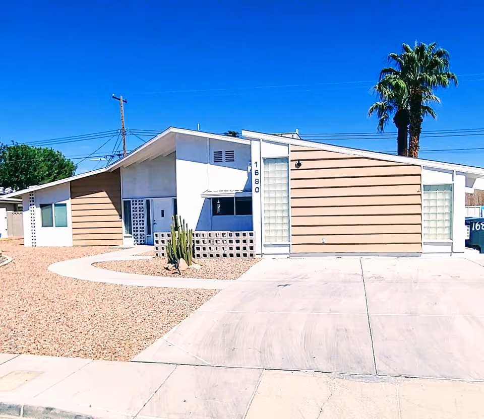 Front exterior of a single-story beige facility with desert landscaping and a curved driveway.