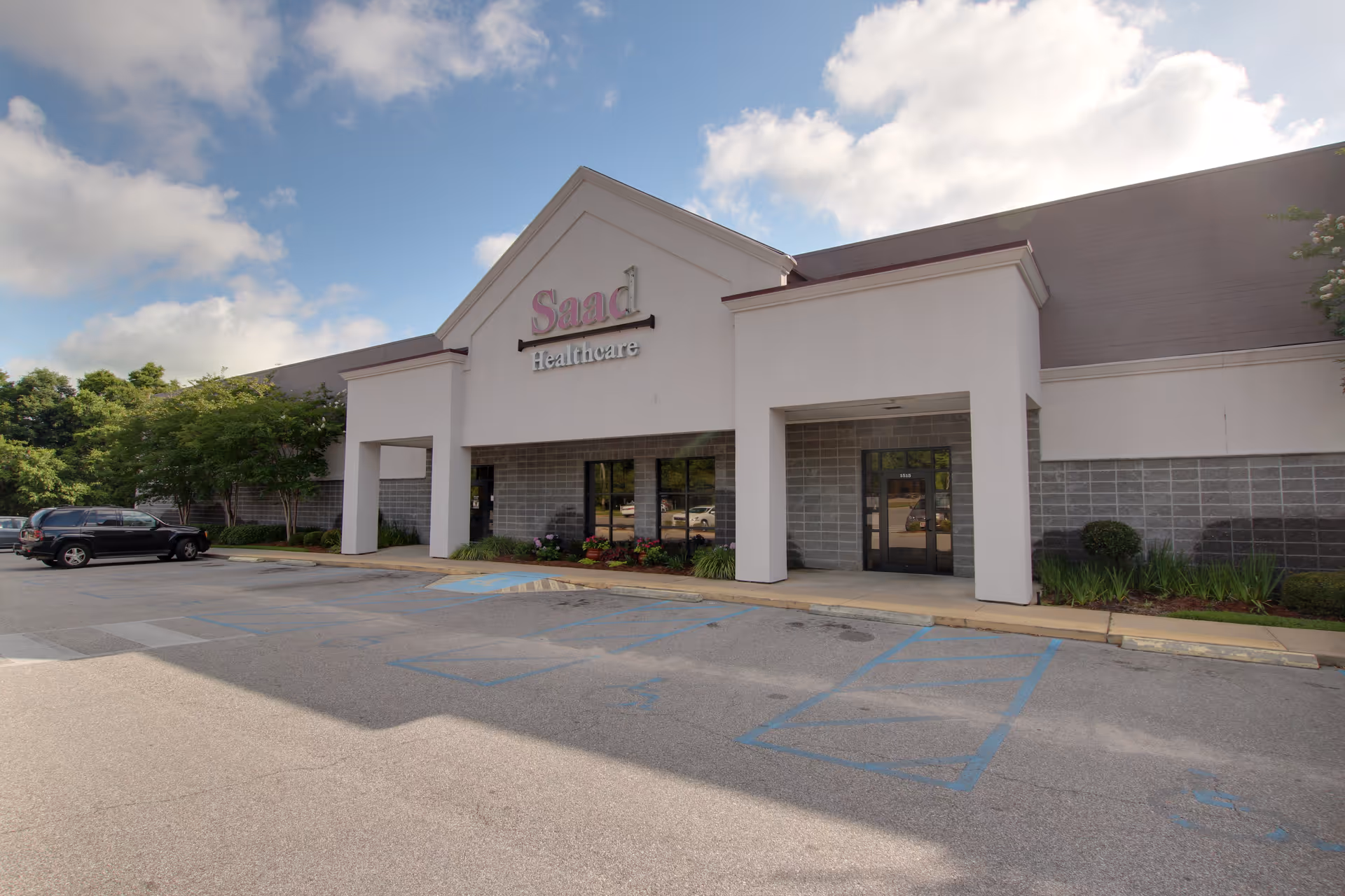 Exterior view of Saad Healthcare building entrance with a parking lot.