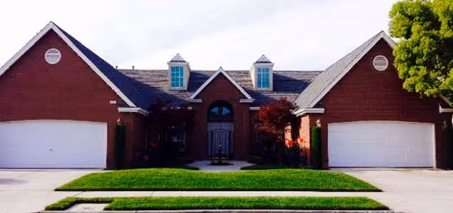 Brick senior living facility exterior with three garage bays and manicured lawn.