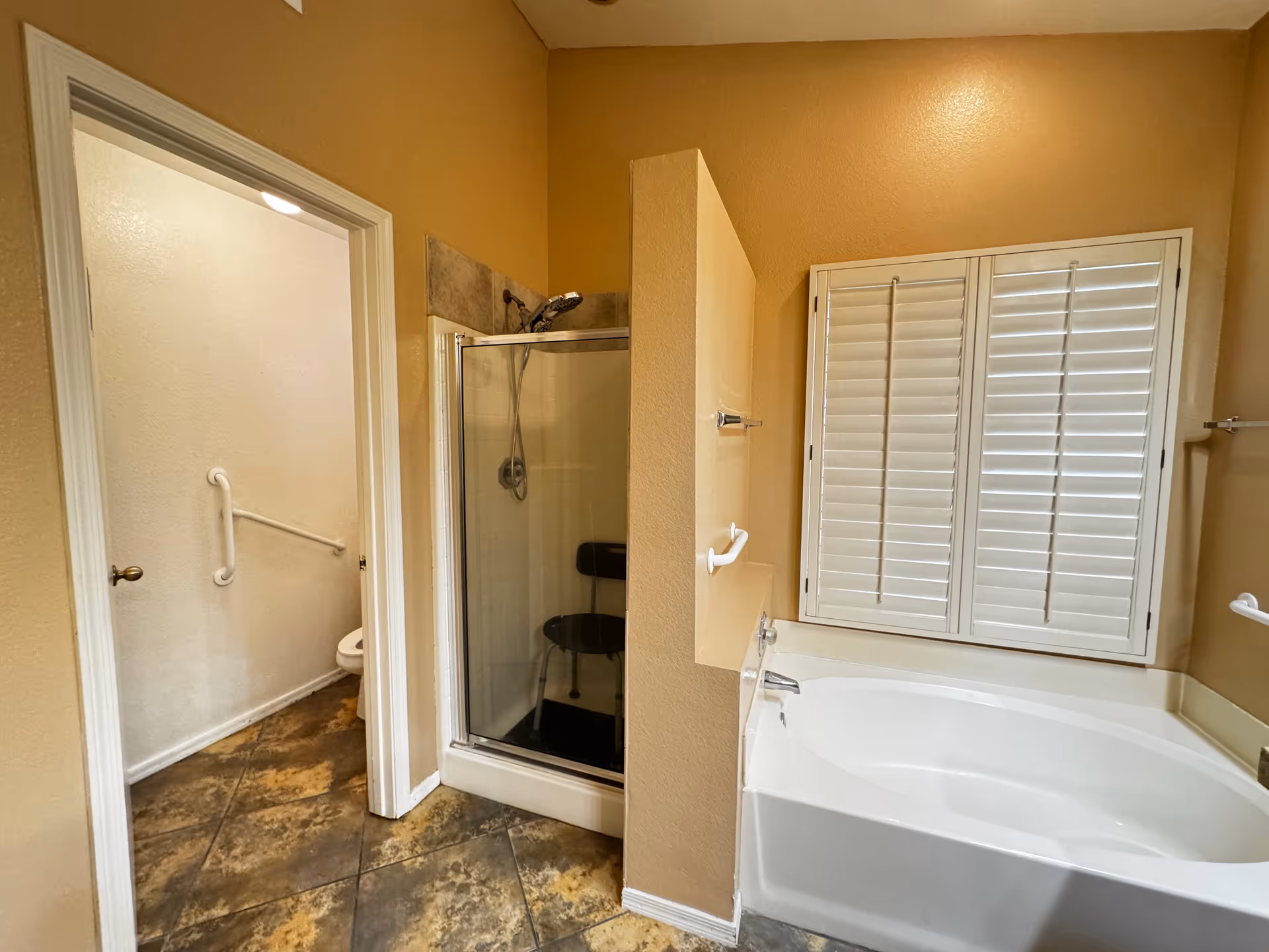 Beige bathroom with a glass shower, large bathtub, and window shutters in St. Charles Place.