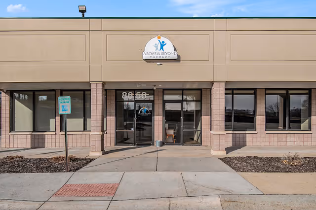 Exterior view of a beige building with Above and Beyond Therapy sign at entrance.