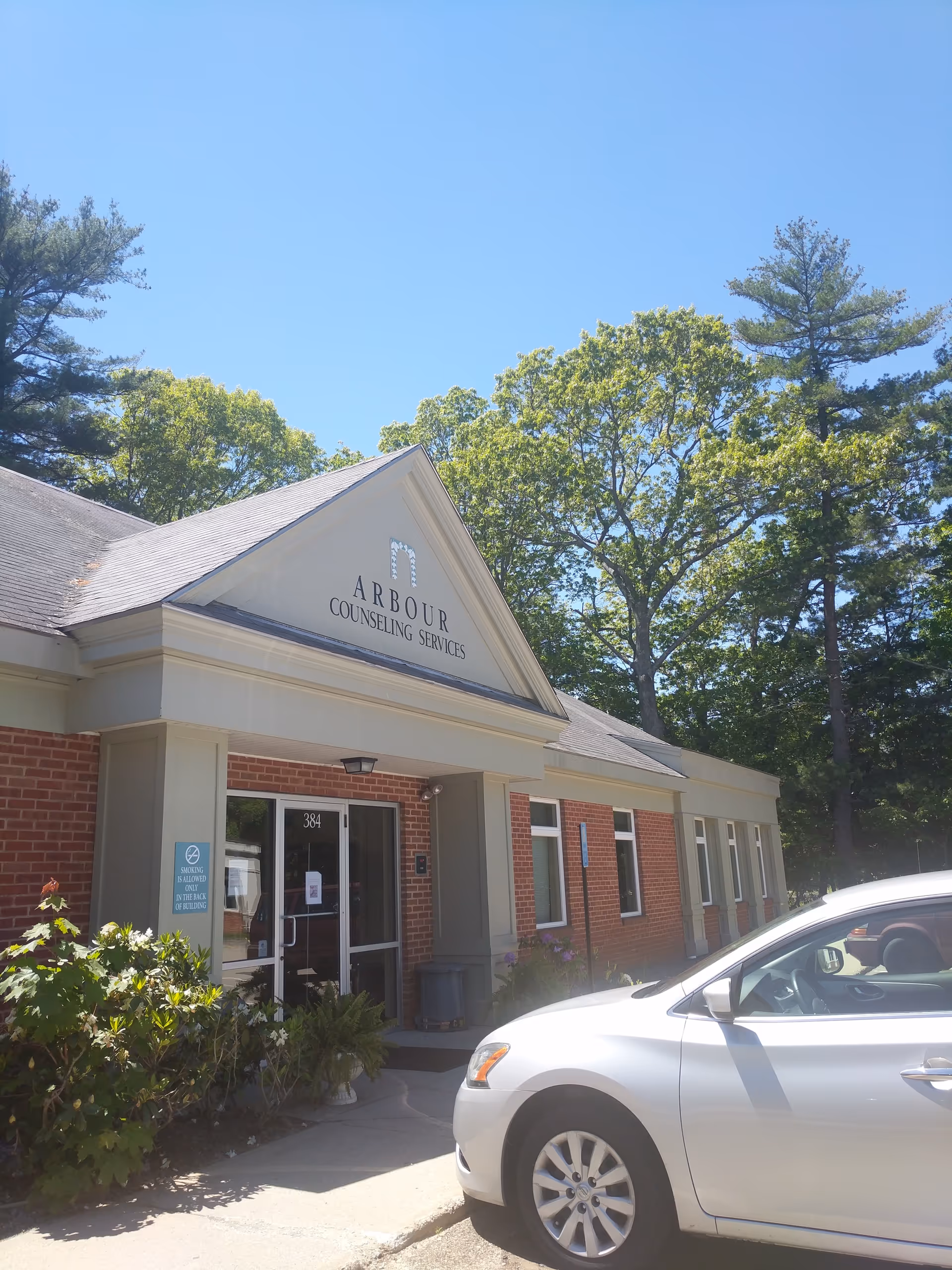 Front view of Arbour Counseling Services building with entrance and parked car.