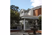 Two-story brick-and-siding senior living building with a covered porch and front fountain.