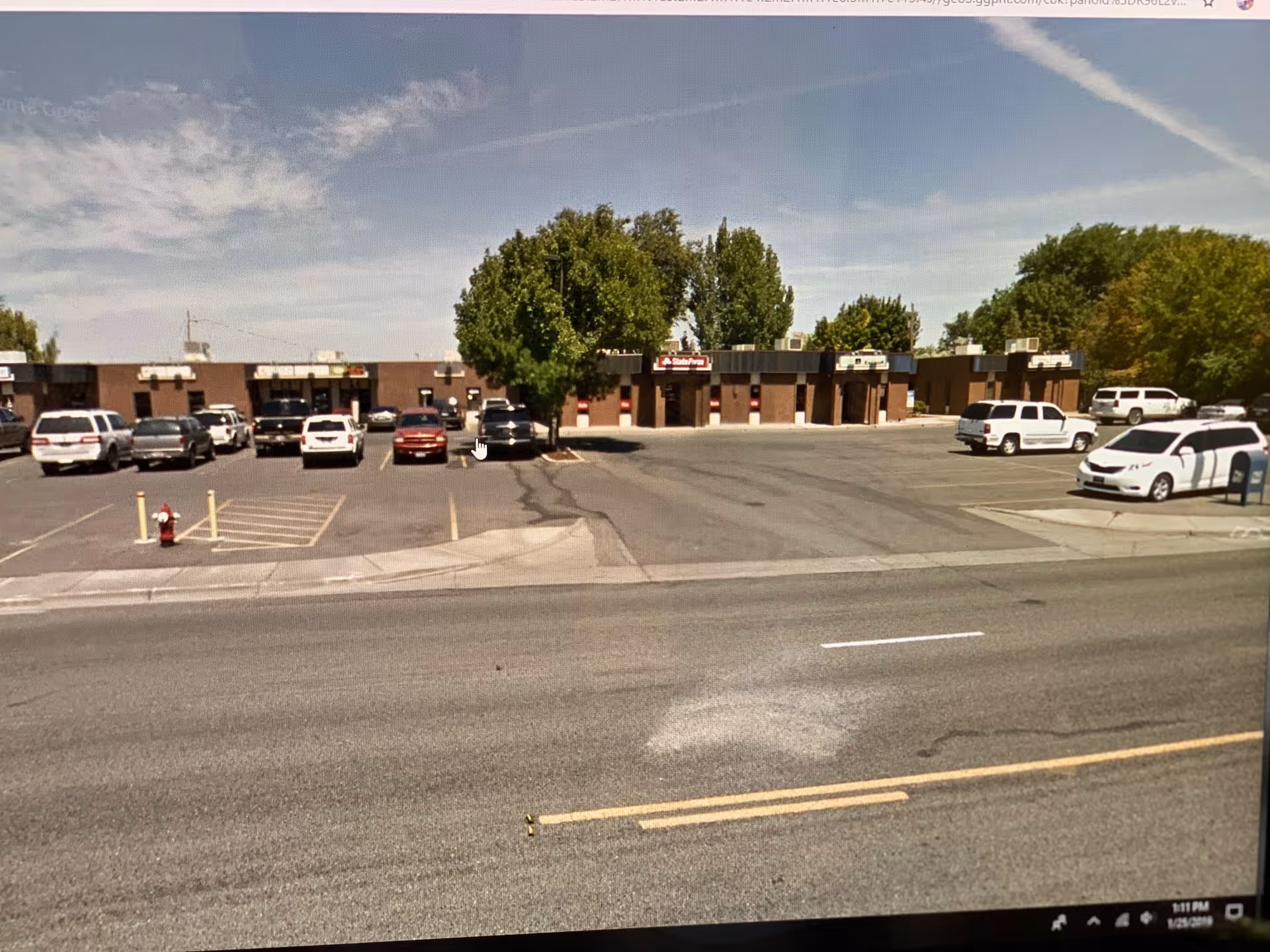Exterior view of a strip mall-style building with a parking lot and parked cars.