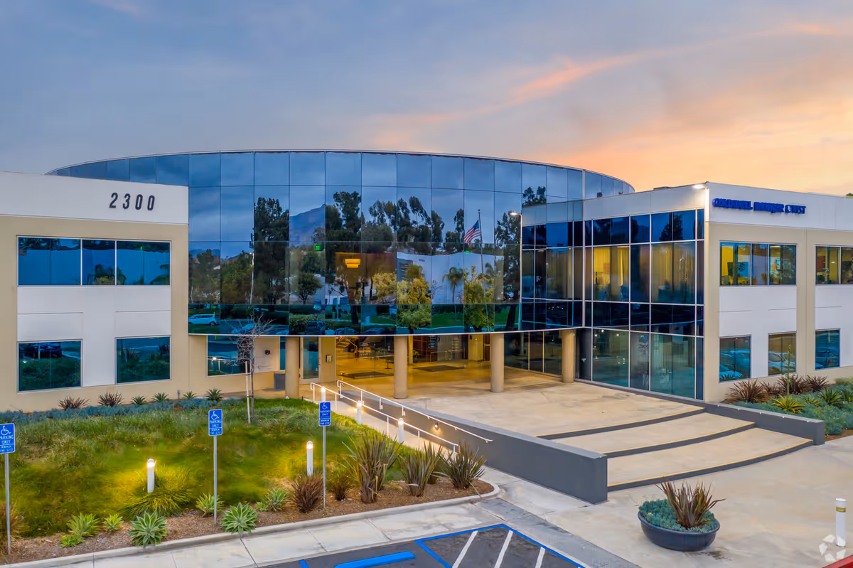 Modern glass-front facility with curved entrance, landscaped grounds, and accessible ramps.