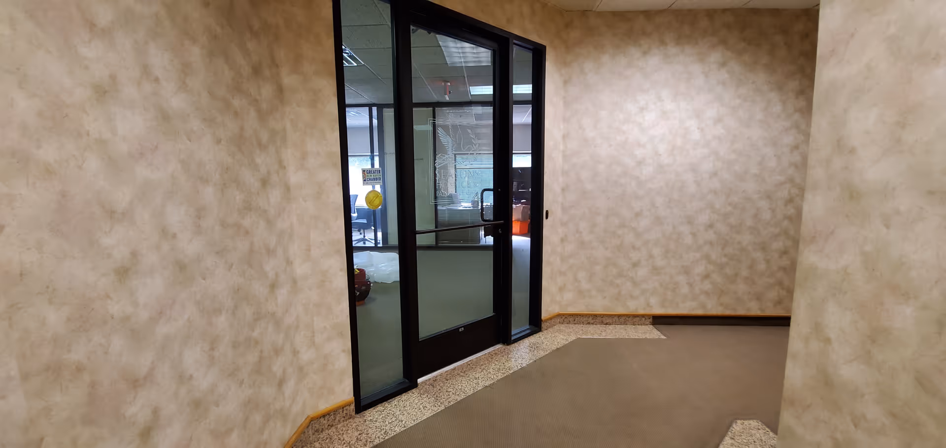 Interior hallway of a senior facility with glass doors and textured beige walls.