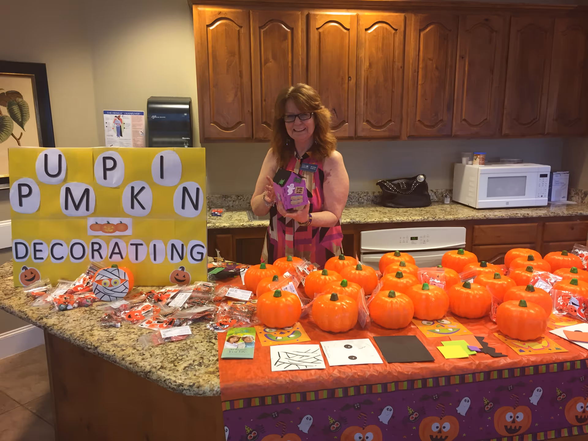 Staff member hosts pumpkin decorating at a kitchen counter with pumpkins.