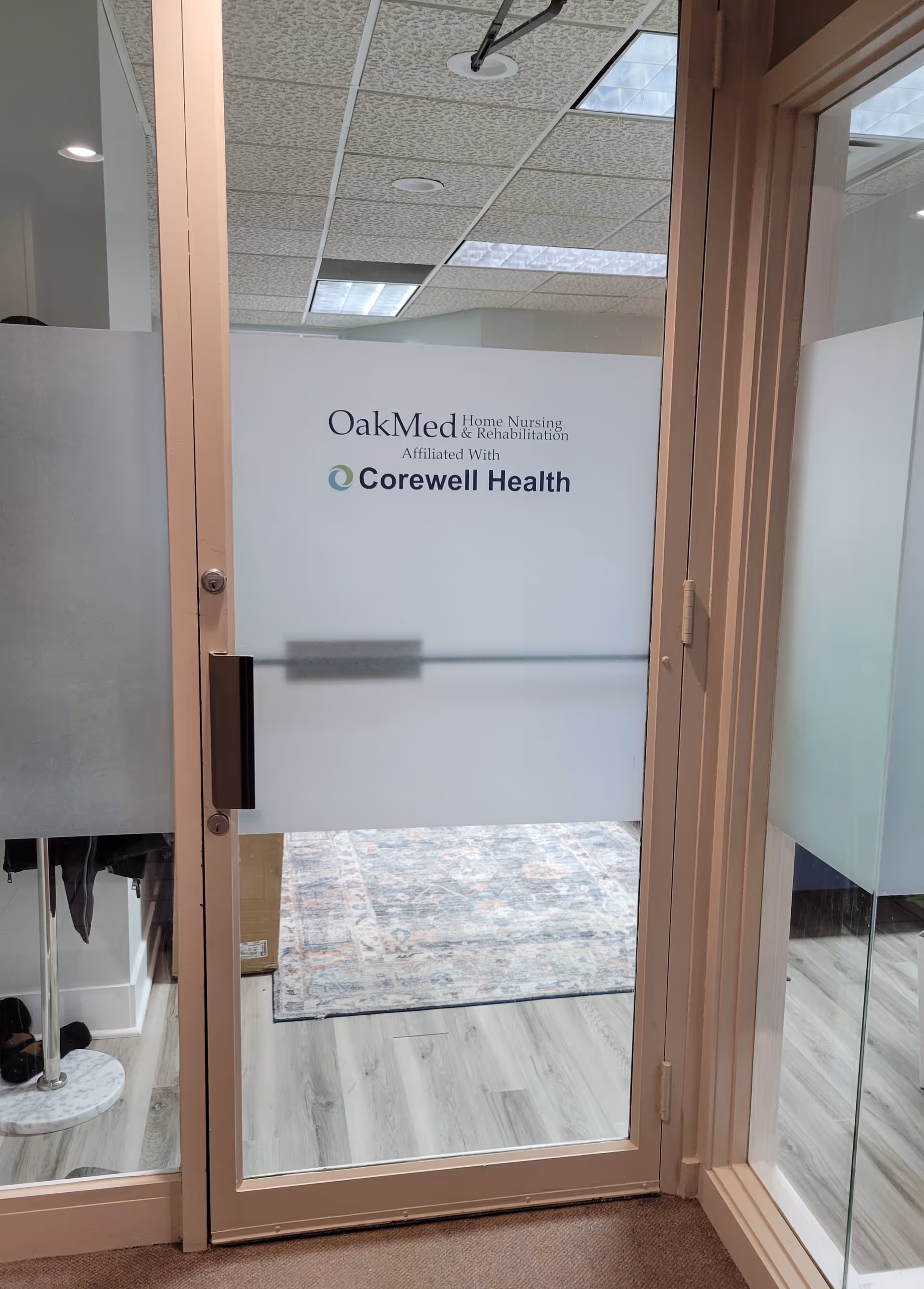 Frosted glass door with OakMed Home Nursing & Rehabilitation and Corewell Health signage.