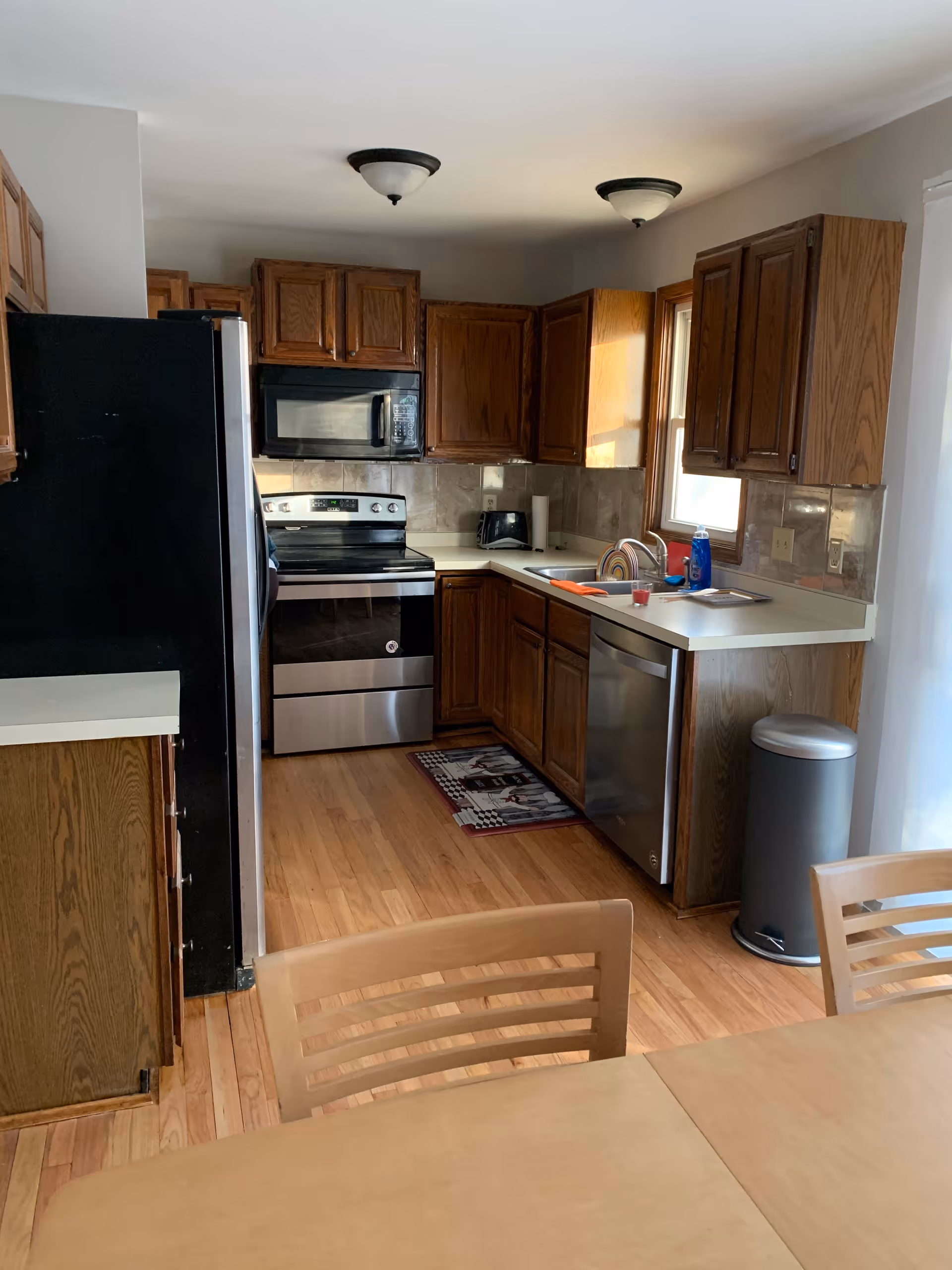 Kitchen with wooden cabinets, stainless appliances, sink, and dining table in a senior living facility.