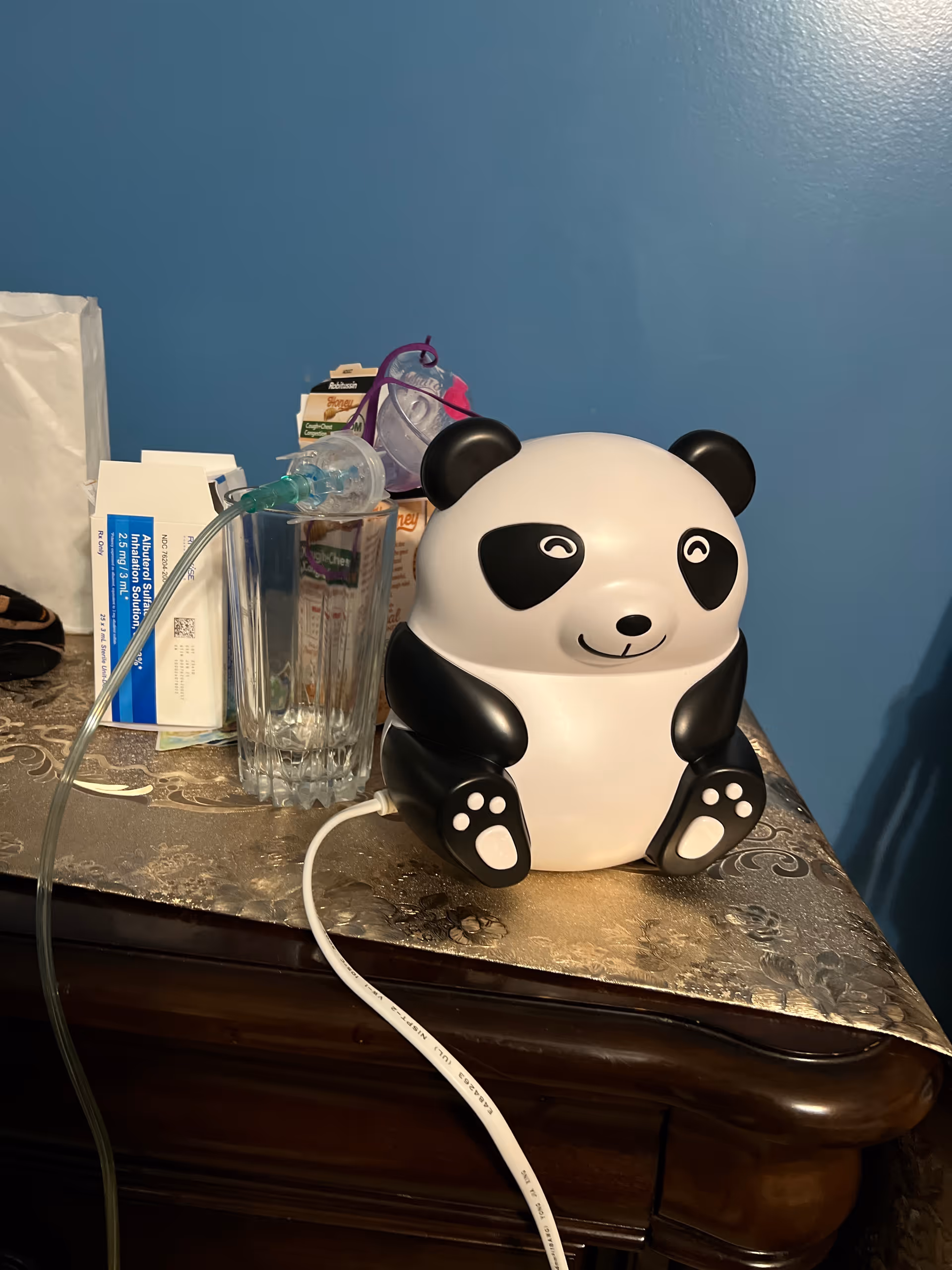A panda-shaped lamp sits on a patterned table with medical supplies