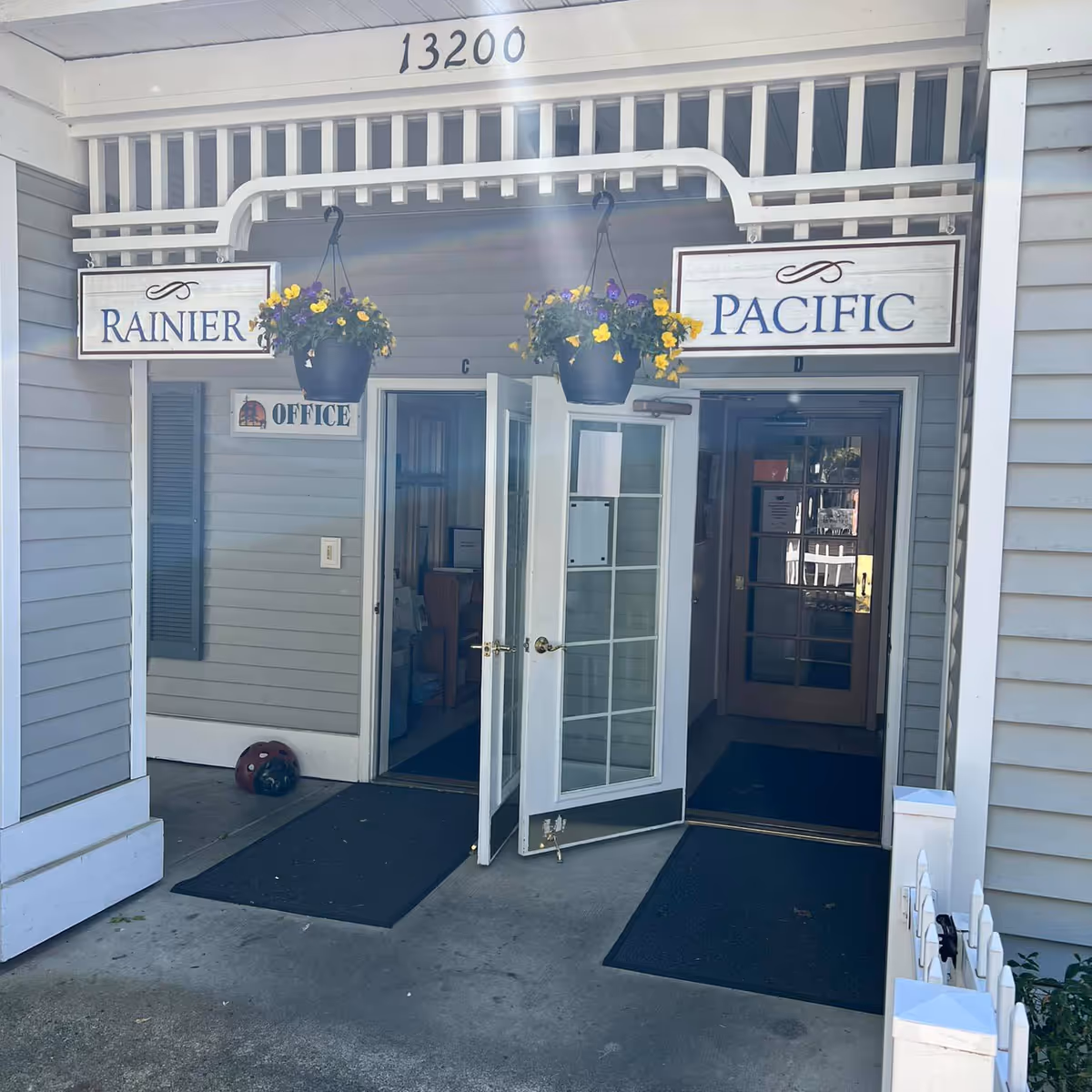 Exterior entrance to Rainier Pacific office with hanging flower baskets and glass doors.