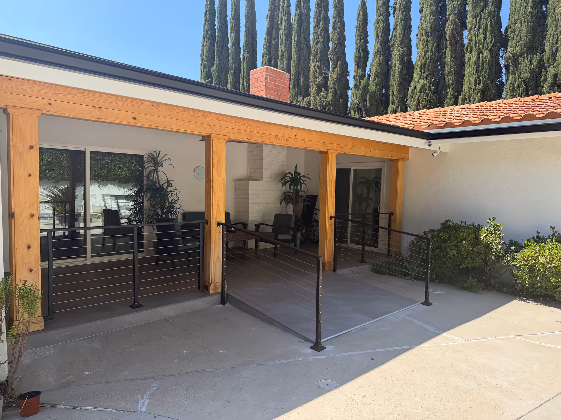 Outdoor covered patio with wooden posts, seating, and glass doors.