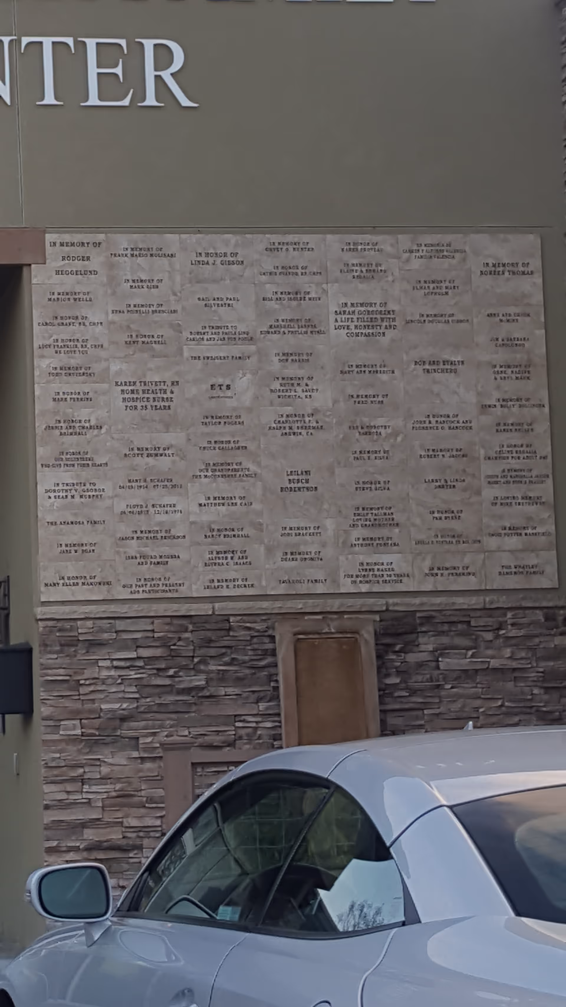 Front exterior of Collabria Care with memorial wall plaques and a parked car.