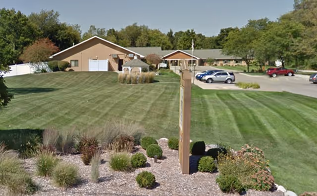 Exterior view of a senior living facility with manicured lawn and entrance.