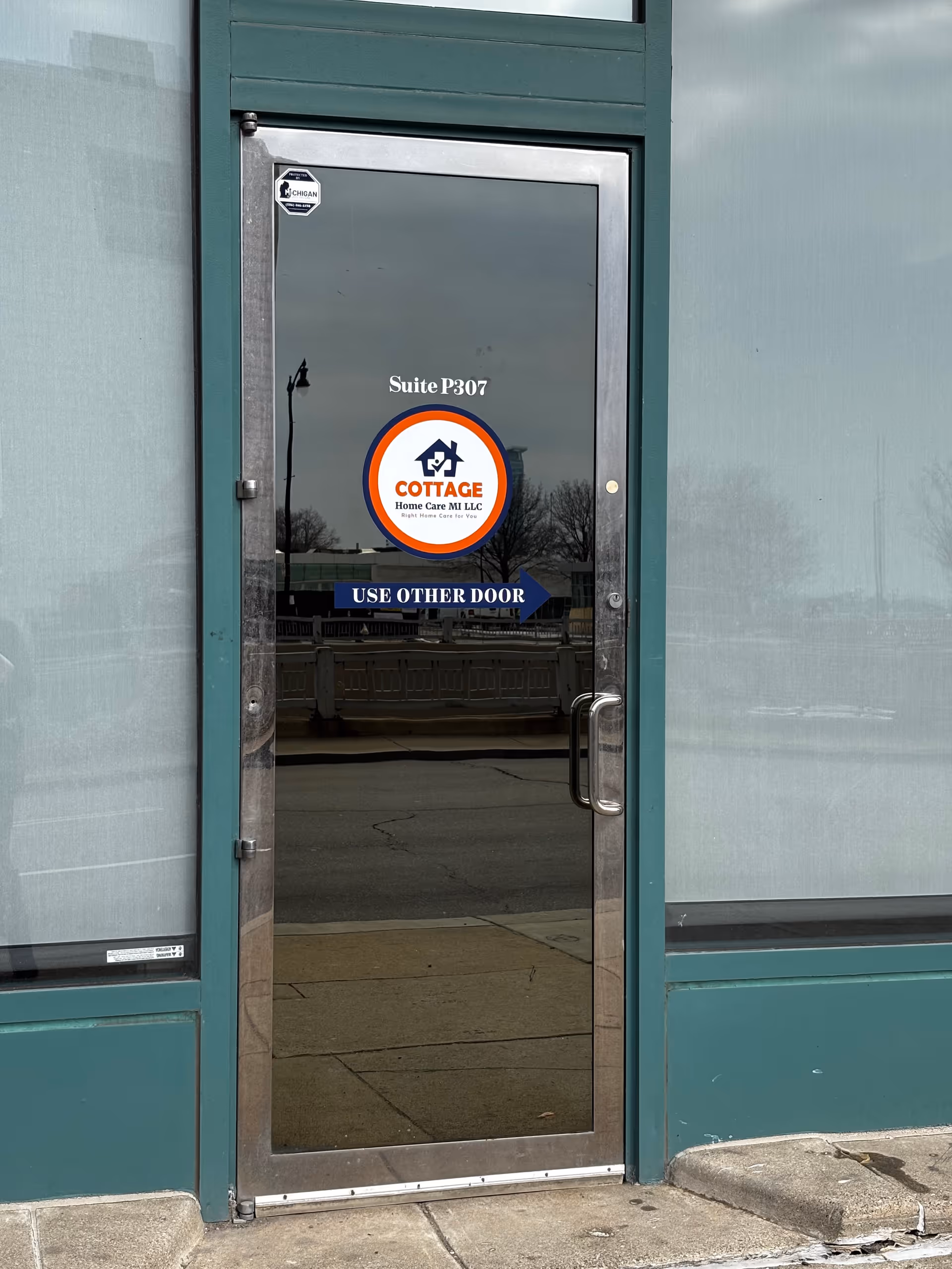 Glass door with Cottage Home Care MI logo, Suite P307, and Use Other Door sign.