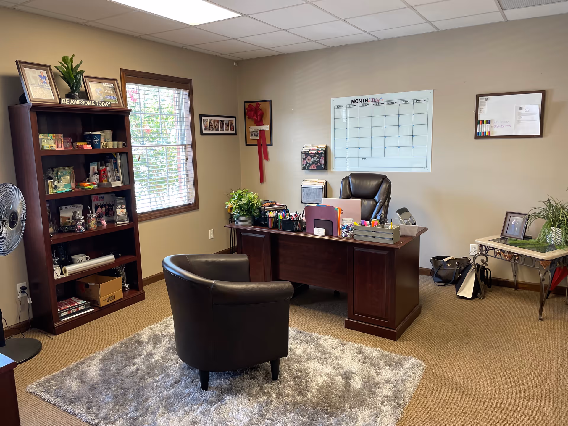 Office reception area with desk, chair, and bookshelf in a senior care facility.