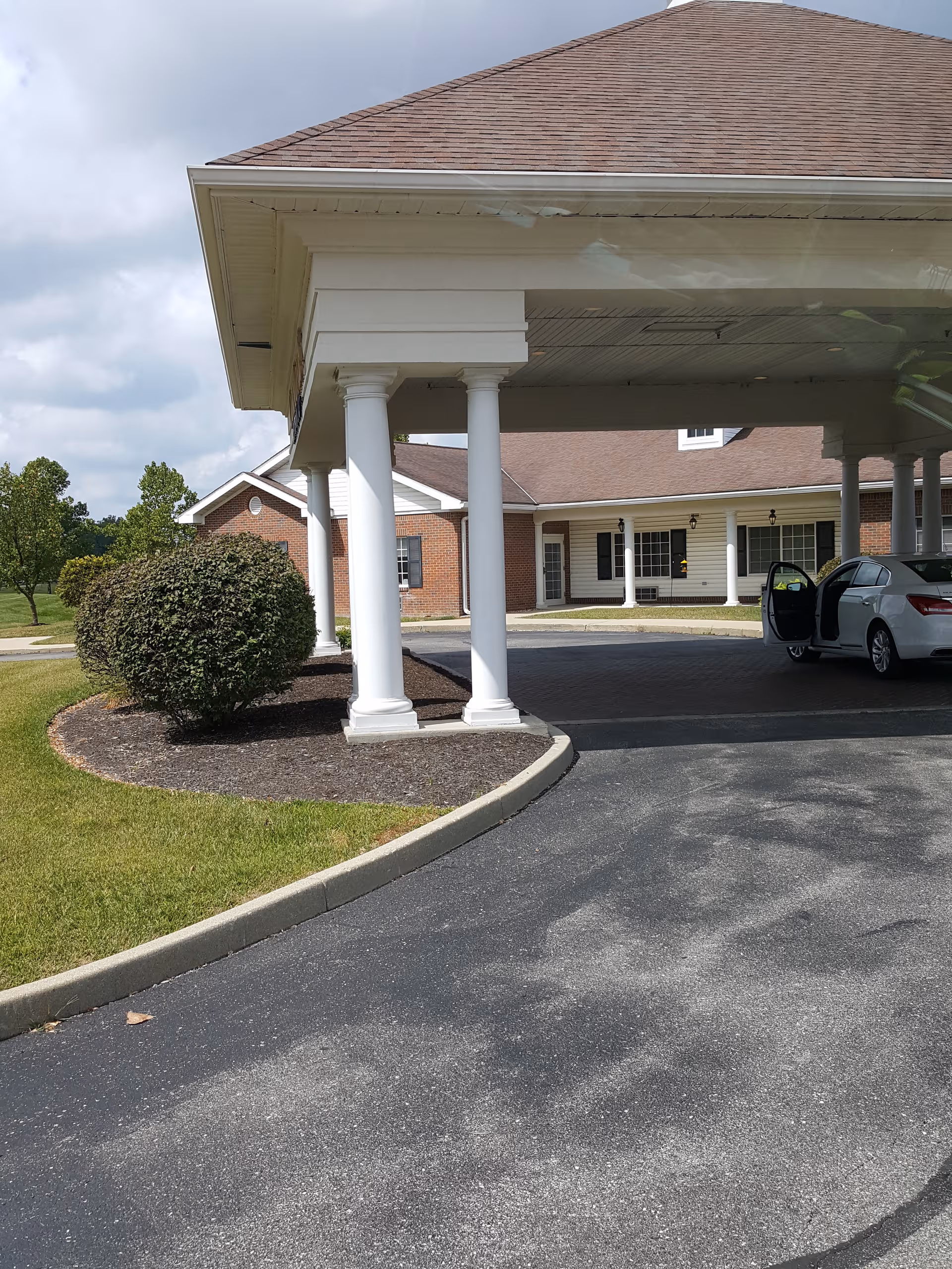 Exterior view of Crown Pointe of Carmel entrance with white columns and driveway.