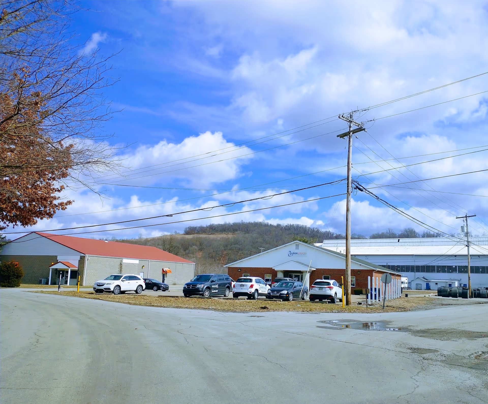 Exterior view of a facility with parked cars and power lines by the entrance.