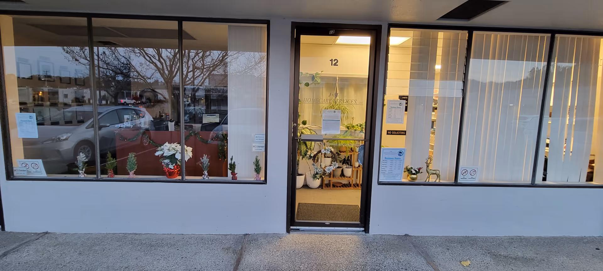 Front view of a glass storefront for J&M Homecare Services with plants and an entrance.