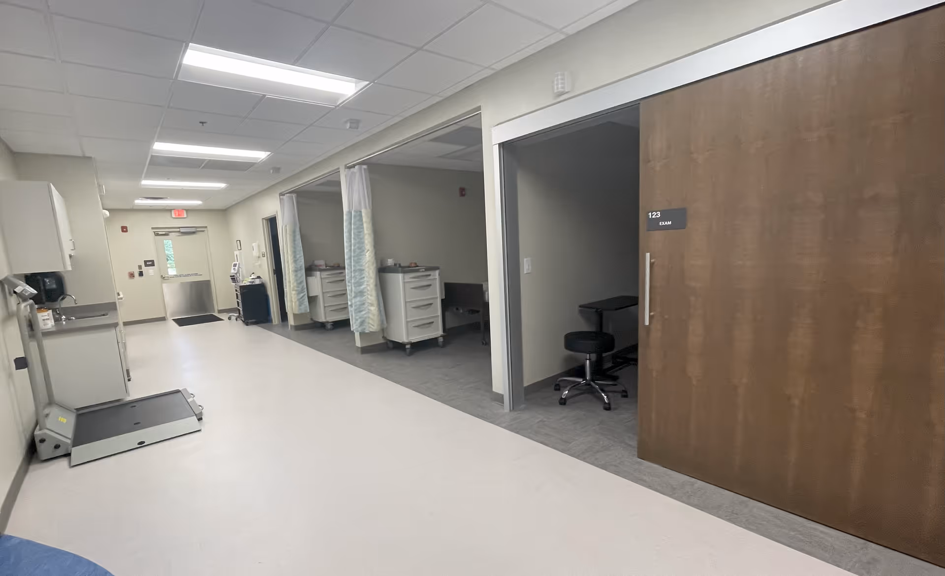 Well-lit interior hallway of a senior care facility with patient rooms and equipment.