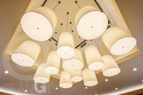 A cluster of large, cylindrical pendant lights hanging from the ceiling, emitting a warm, soft light in an indoor setting.