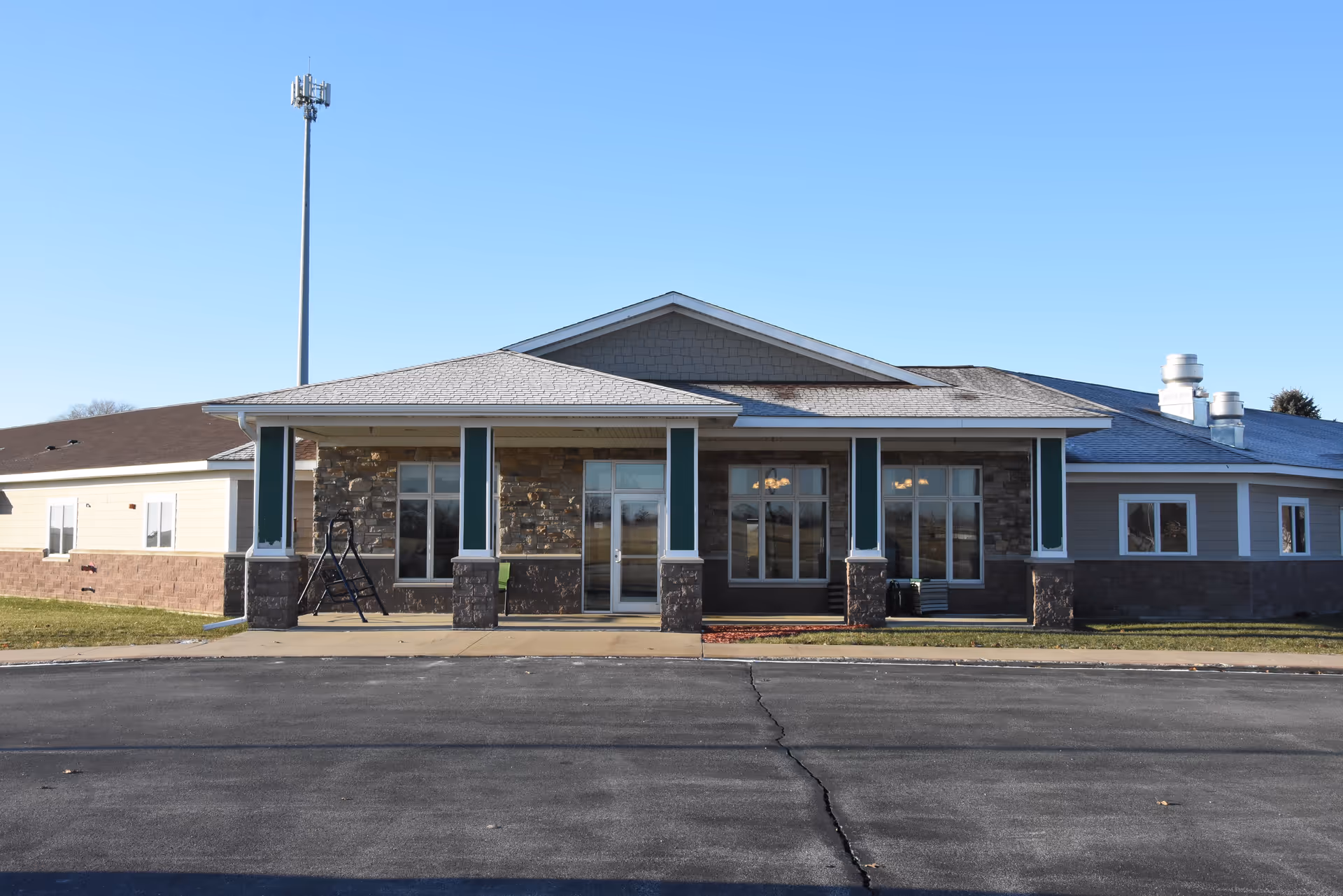 Single-story senior living facility front façade with stone accents and glass entry doors.