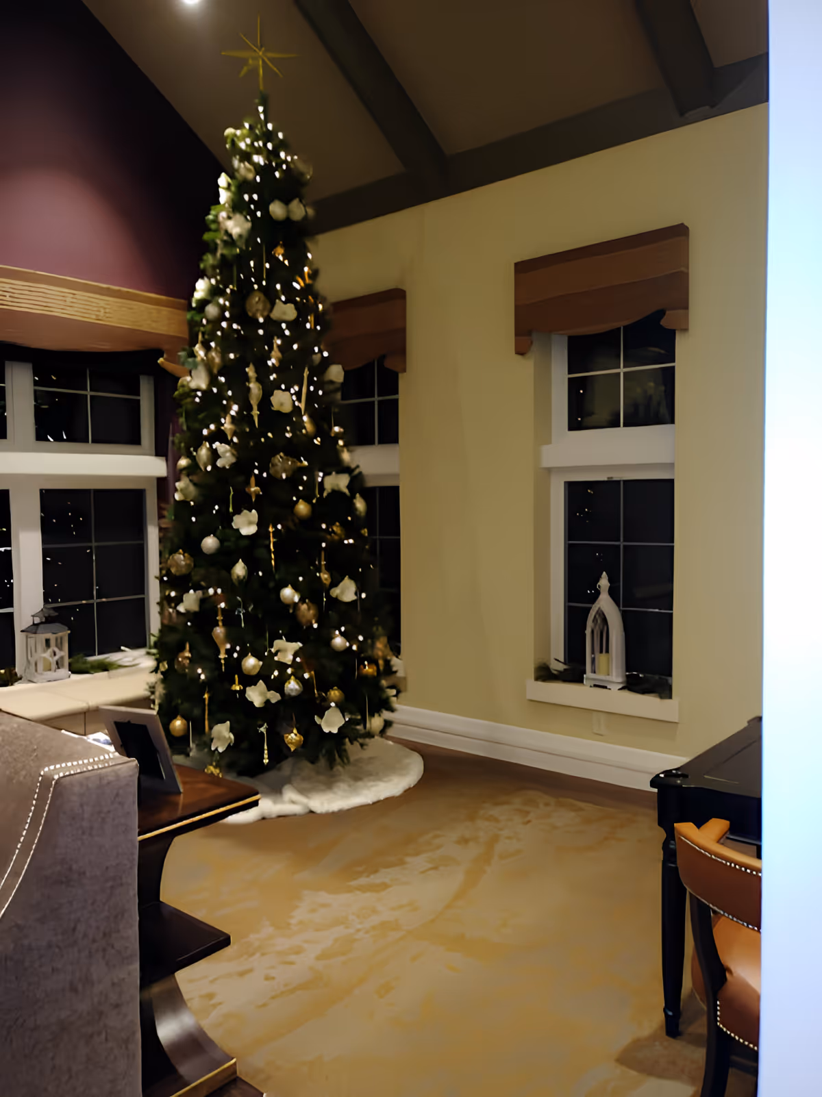 Decorated Christmas tree in a furnished common room with windows, chairs, and a carpeted floor.