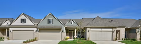 Row of townhouse-style senior living buildings with garages and manicured lawns.