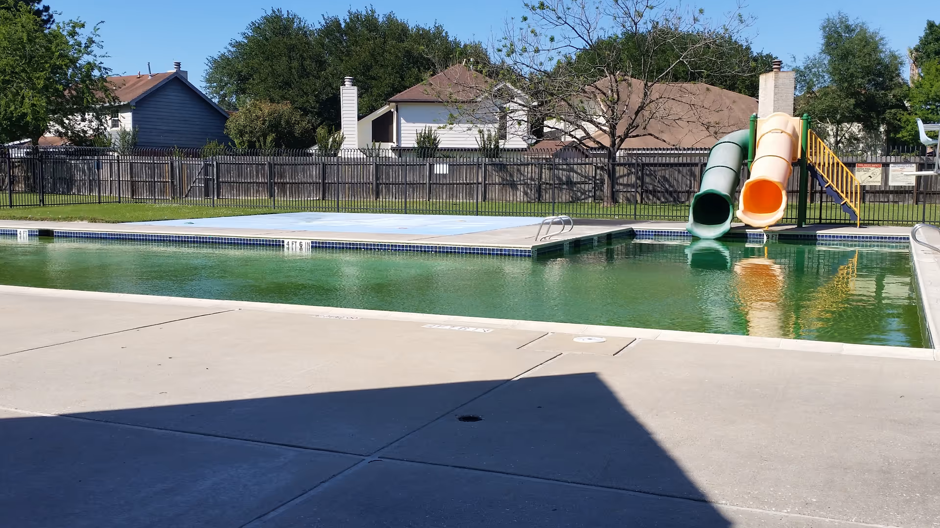 Outdoor pool area with colorful water slides and surrounding concrete deck.