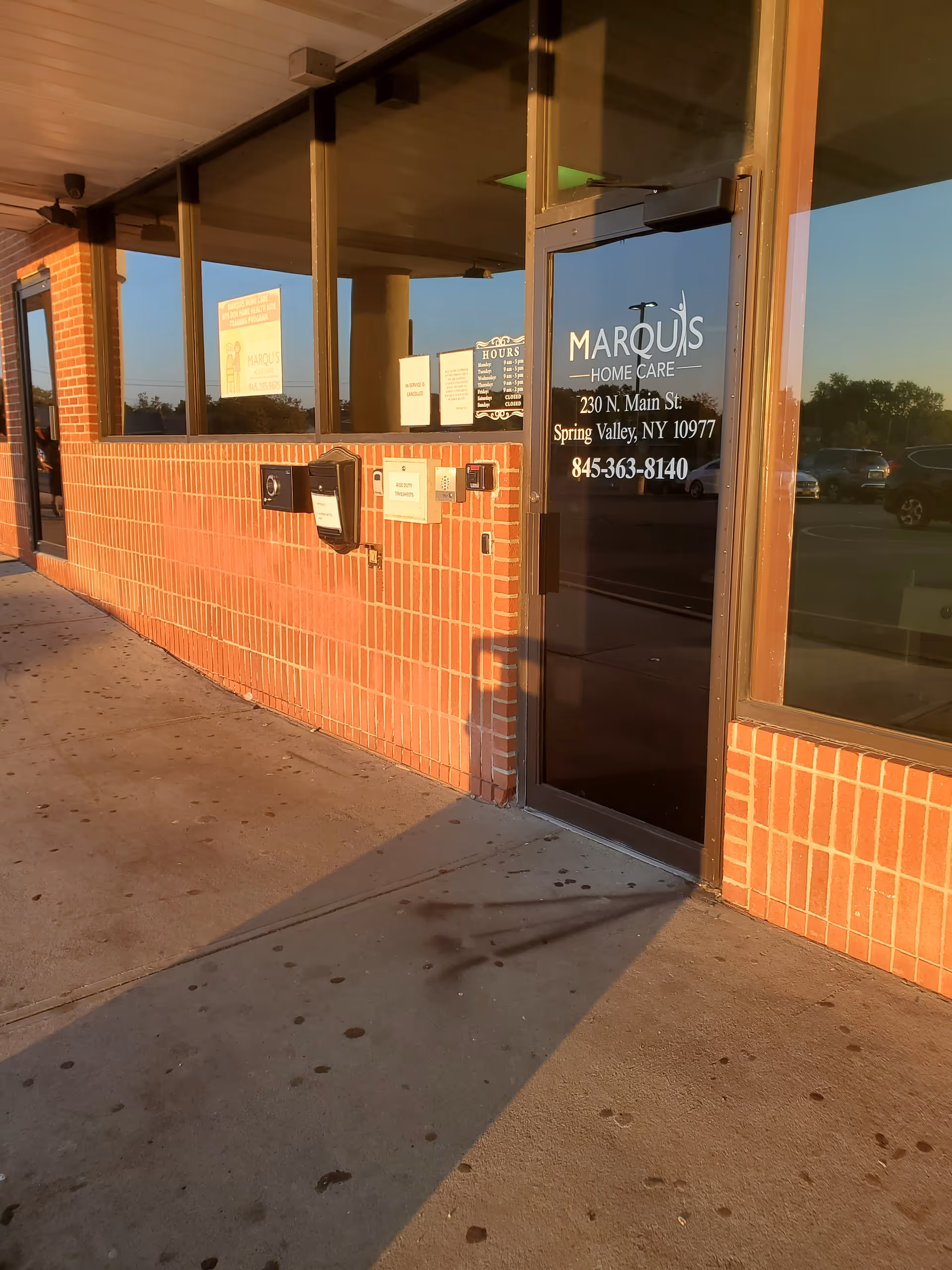 Brick exterior of Marquis Home Care with glass entrance door and windows.
