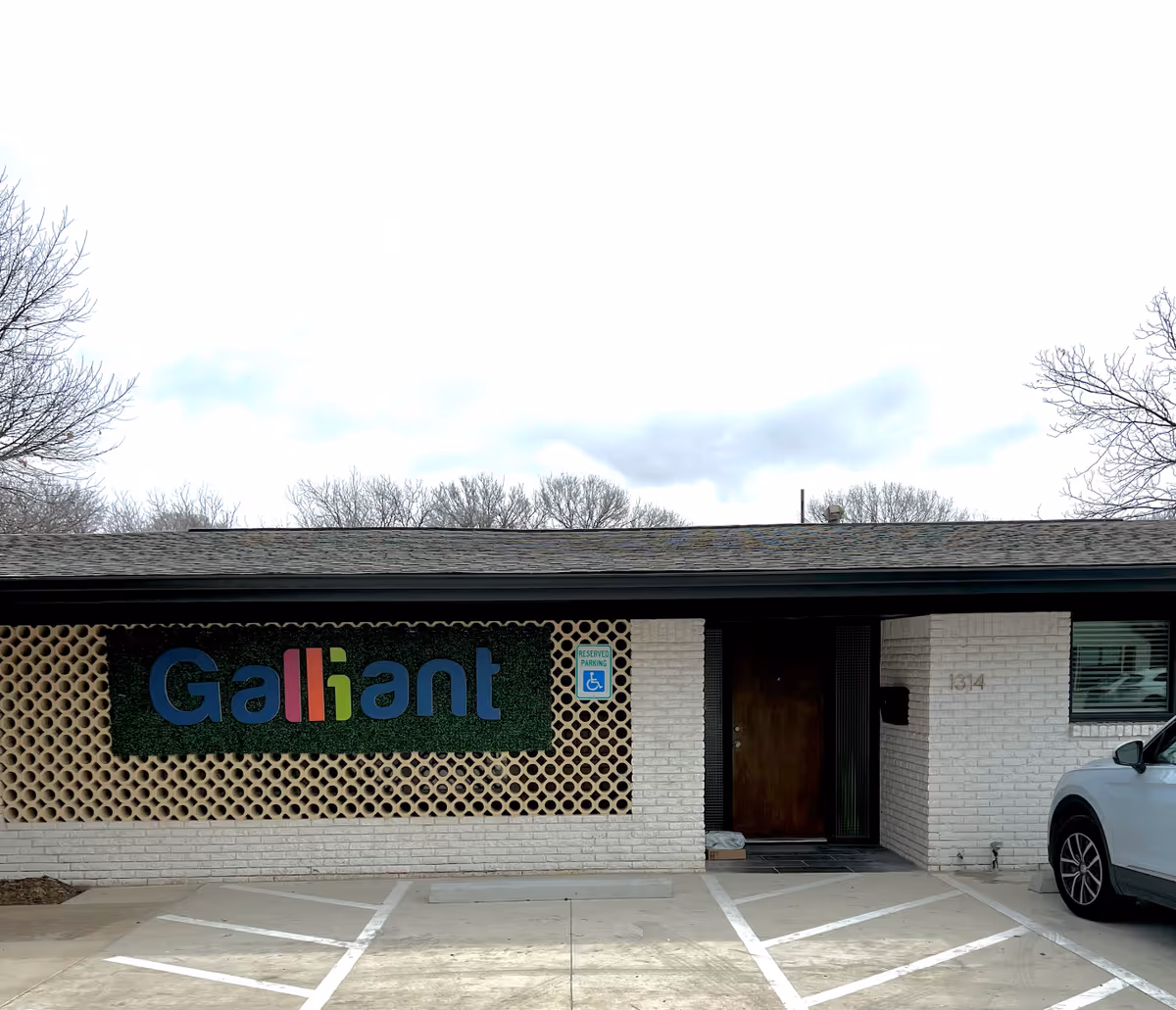 One-story building exterior with a Gallant sign and a parked car.