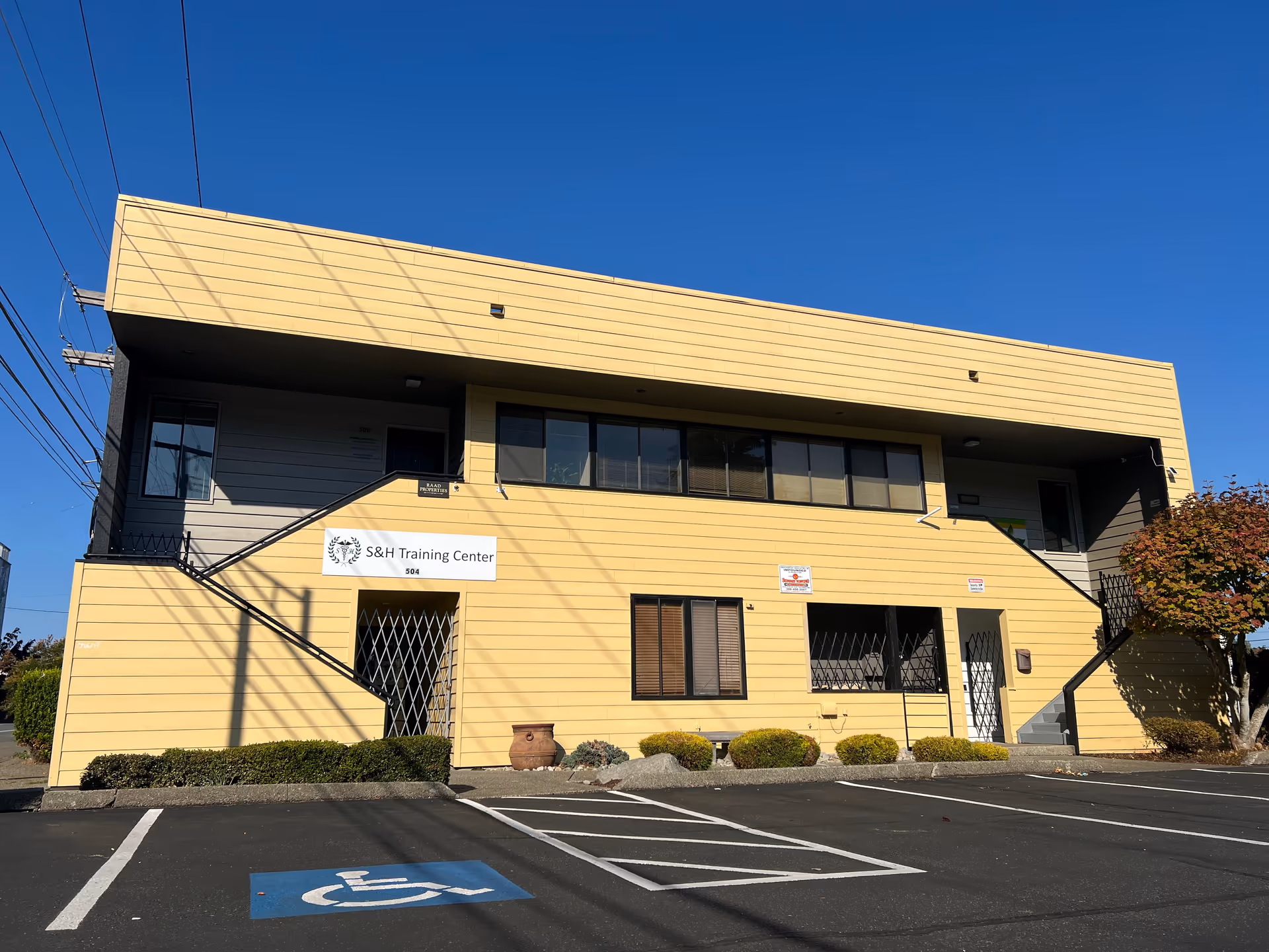 Two-story beige building with S&H Training Center sign and available parking in front.