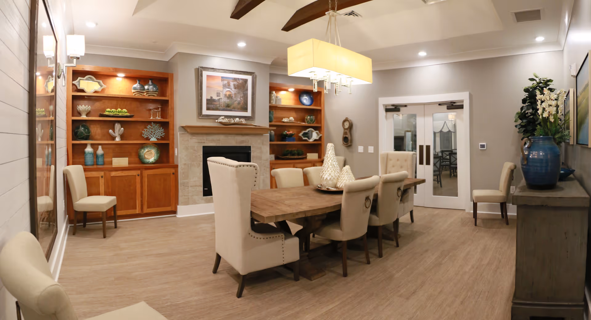 Cozy dining room featuring a large wooden table, upholstered chairs, fireplace, and built-in shelves.