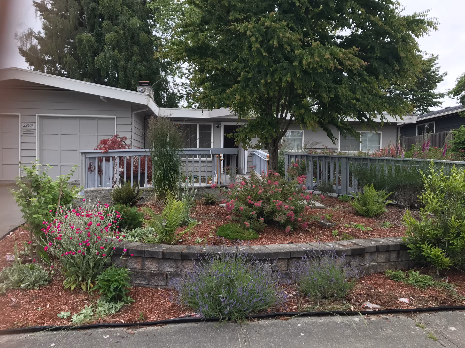 One-story gray senior living home with a landscaped front garden and wooden railing.