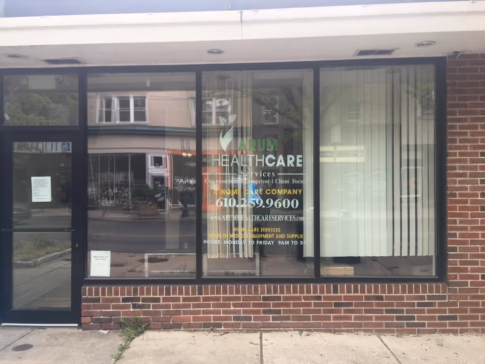 Brick storefront with large front windows displaying Arum Healthcare Services signage