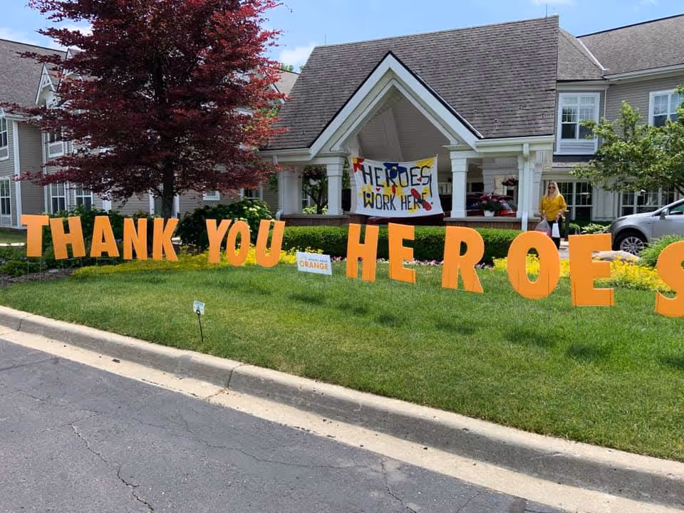 Front view of Open Arms Hospice with large orange 'THANK YOU HEROES' letters on the lawn.