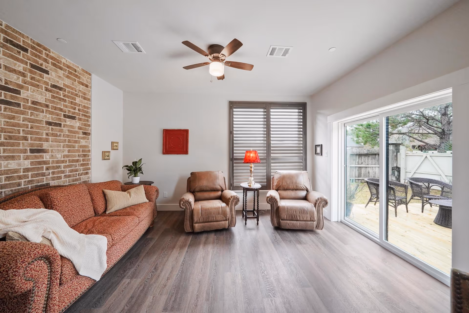 Cozy living room with brick fireplace, comfortable seating, and sliding glass doors to a patio.