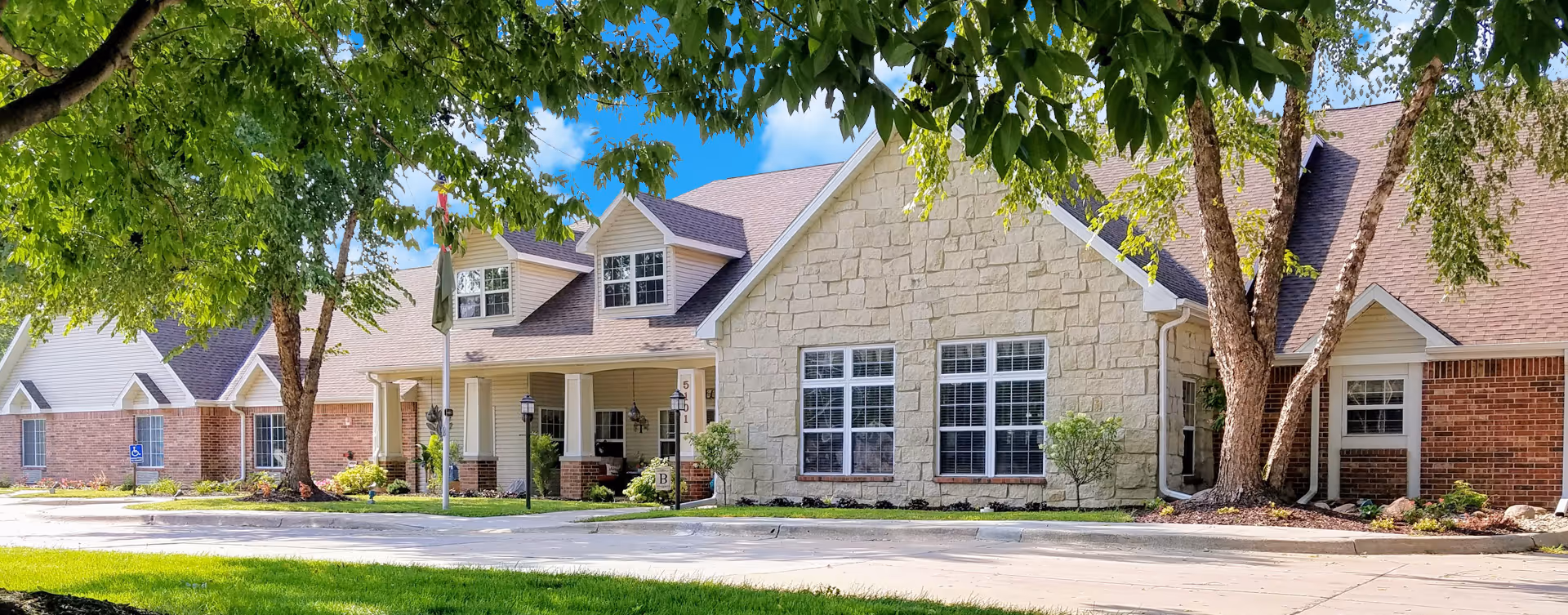 Exterior view of Bickford of Cedar Falls building with stone facade and trees.