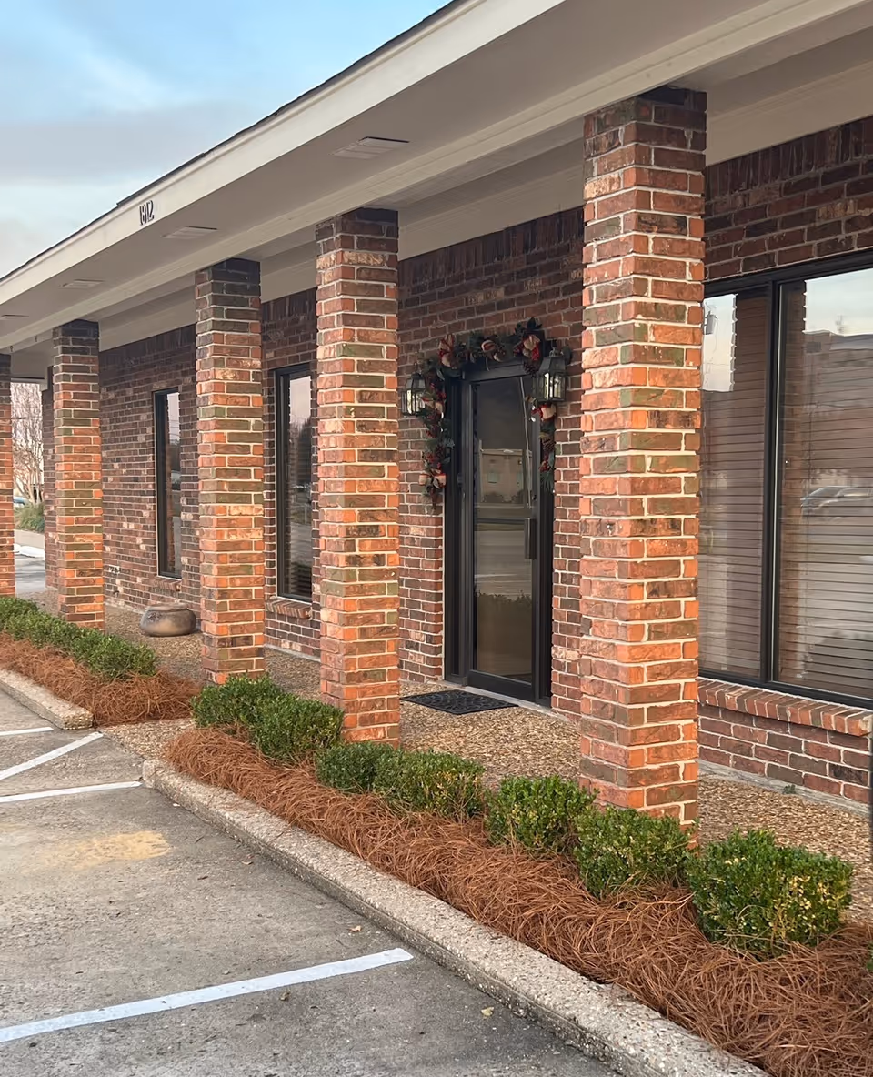 Brick-faced assisted-living facility entry with pillars and wreath beside front door.