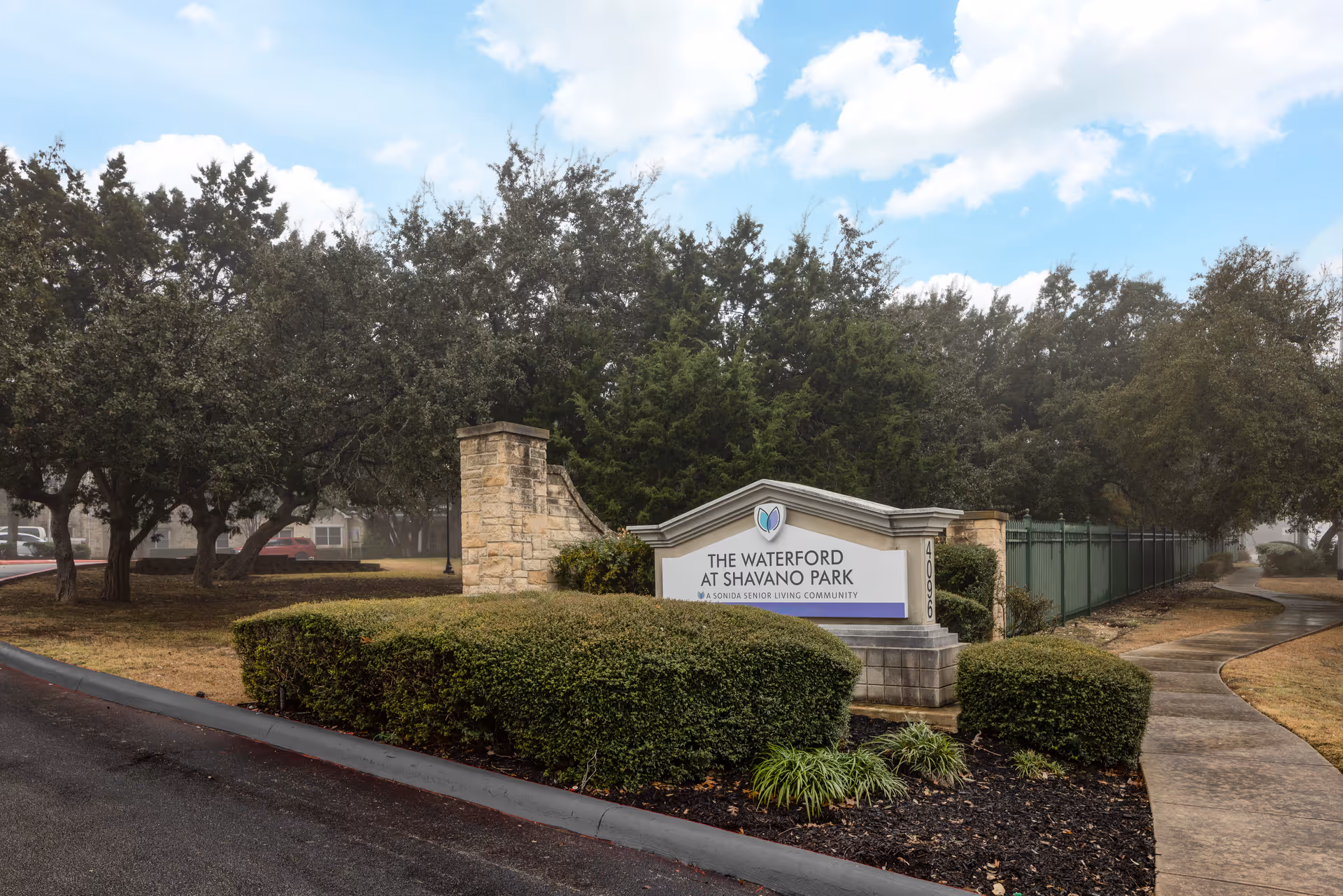 Entrance sign for The Waterford at Shavano Park with landscaped shrubs and trees.