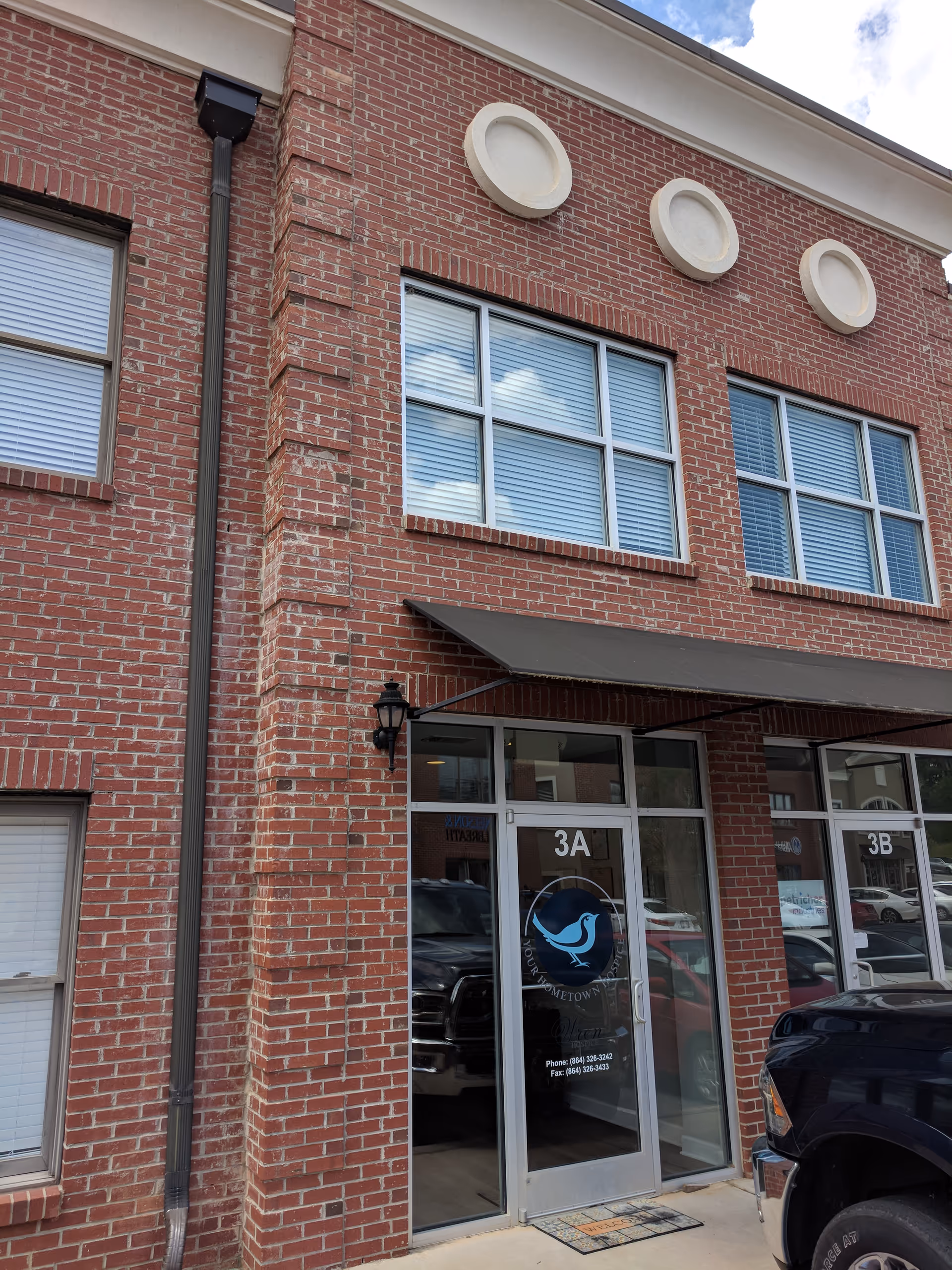 Brick facility exterior with glass entrance doors labeled 3A and 3B, Wren Hospice logo.