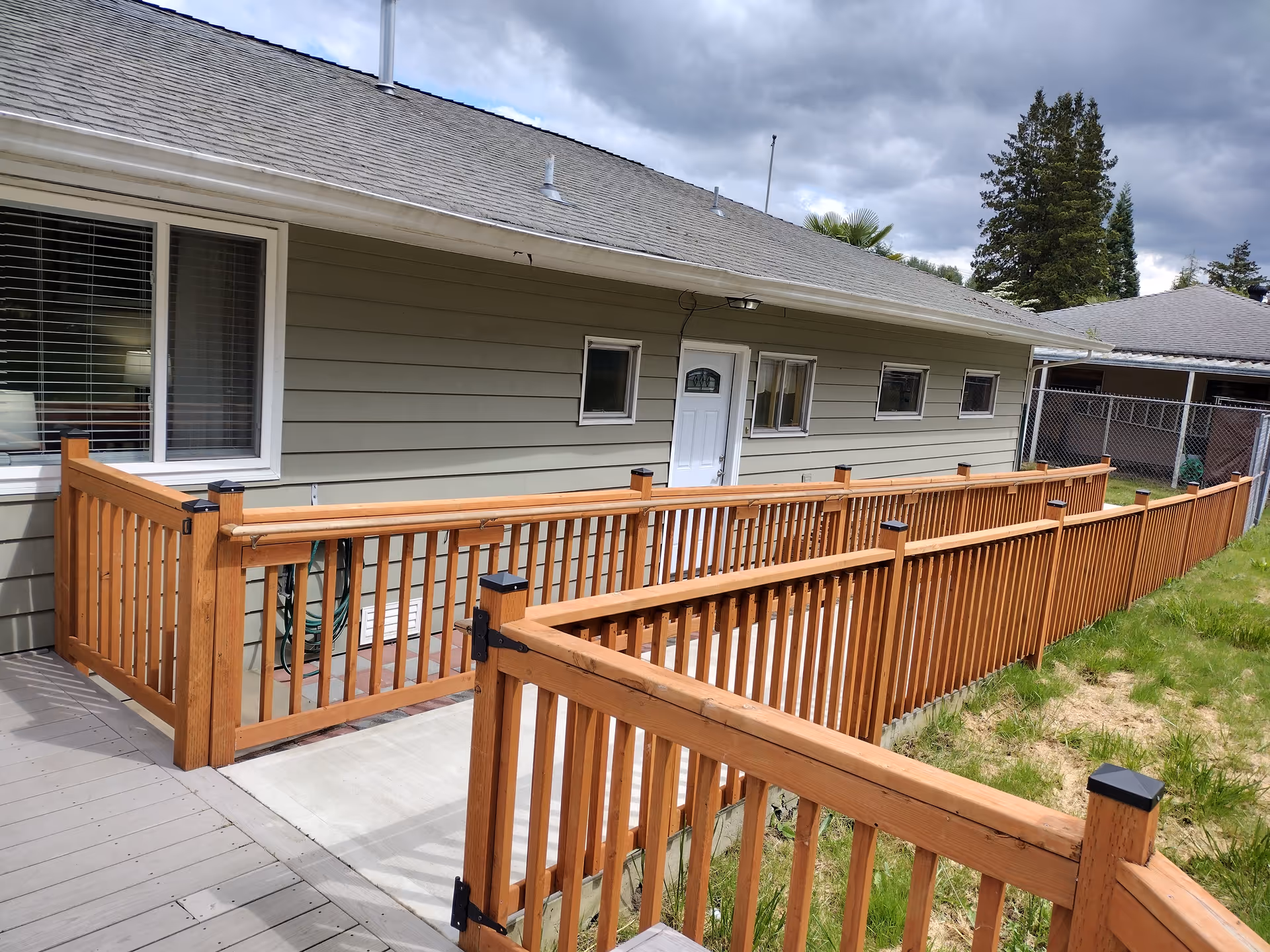 Exterior view of a single-story building with a long wooden deck and railing.