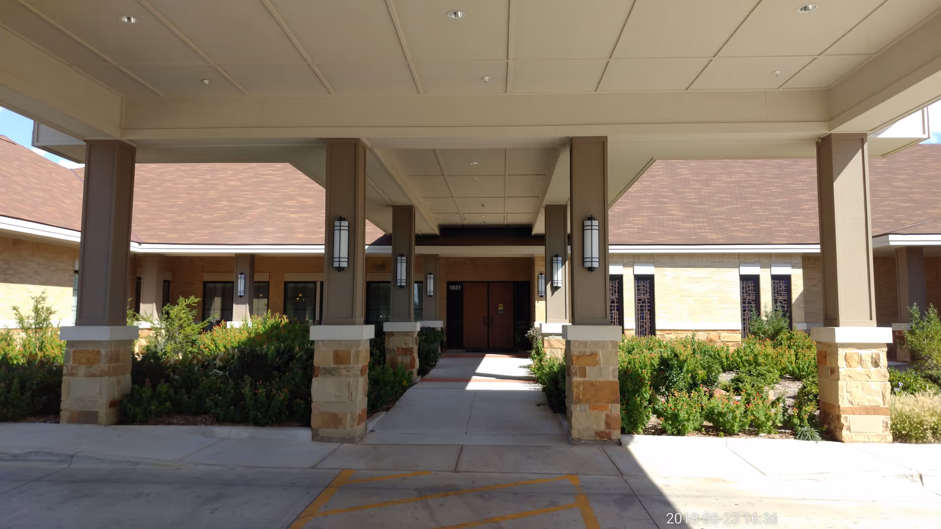 Entrance to Hendrick Hospice Care with a covered walkway, columns, and shrubs.