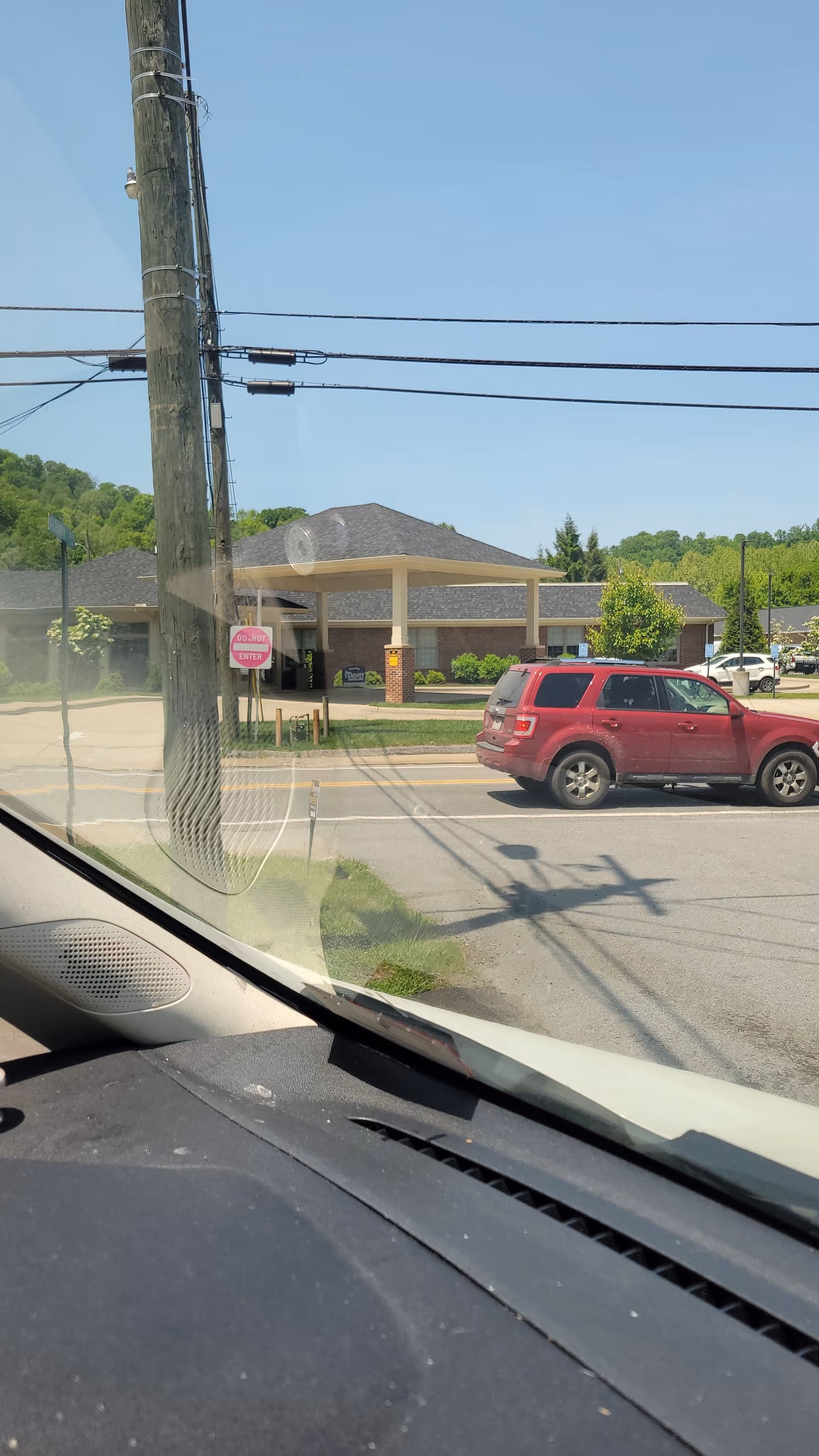 Exterior view of a senior facility with porte-cochère and a red SUV parked.